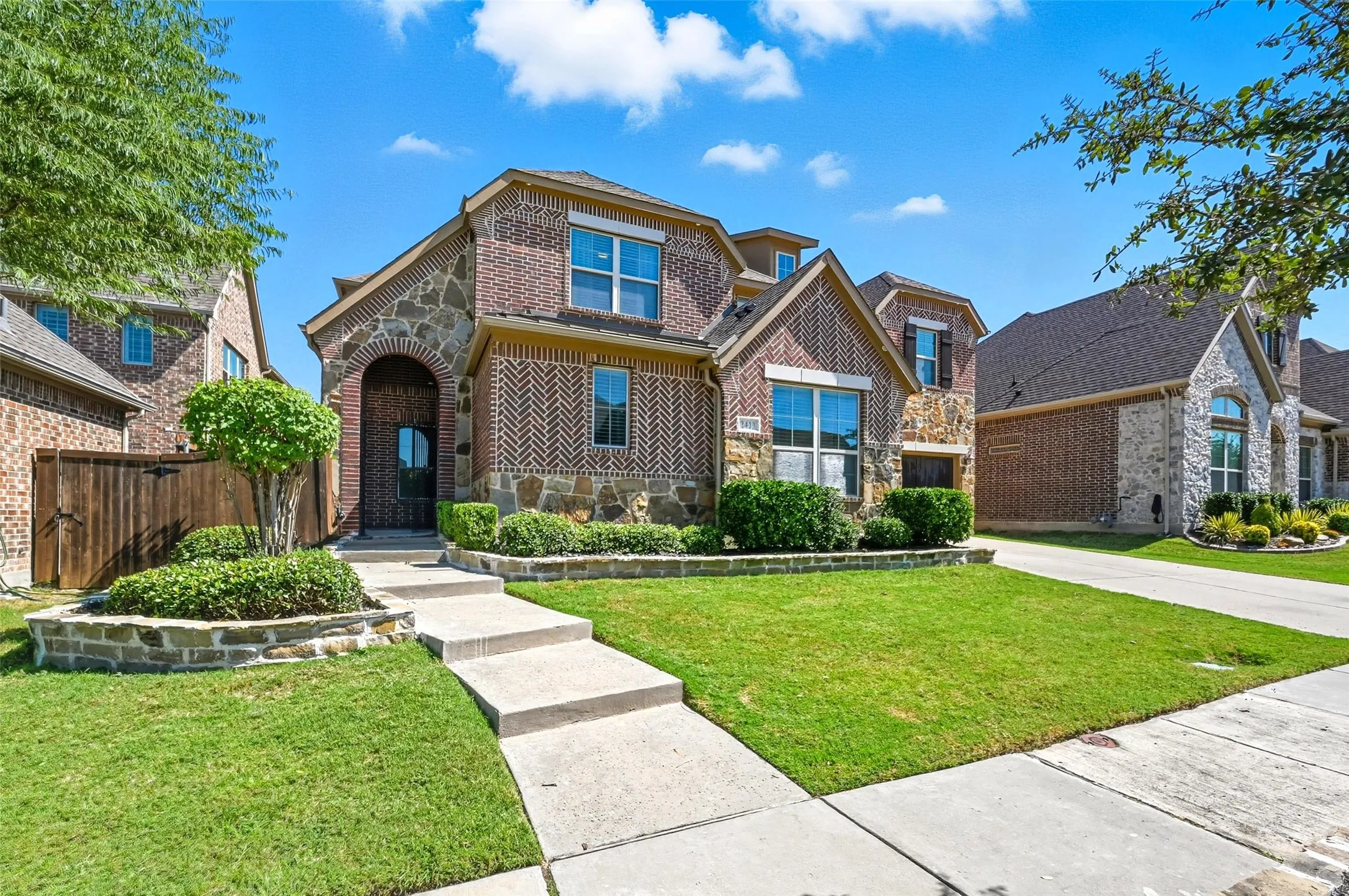 Two-story residence featuring a brick and stone exterior, arched entry, and multi-pane windows