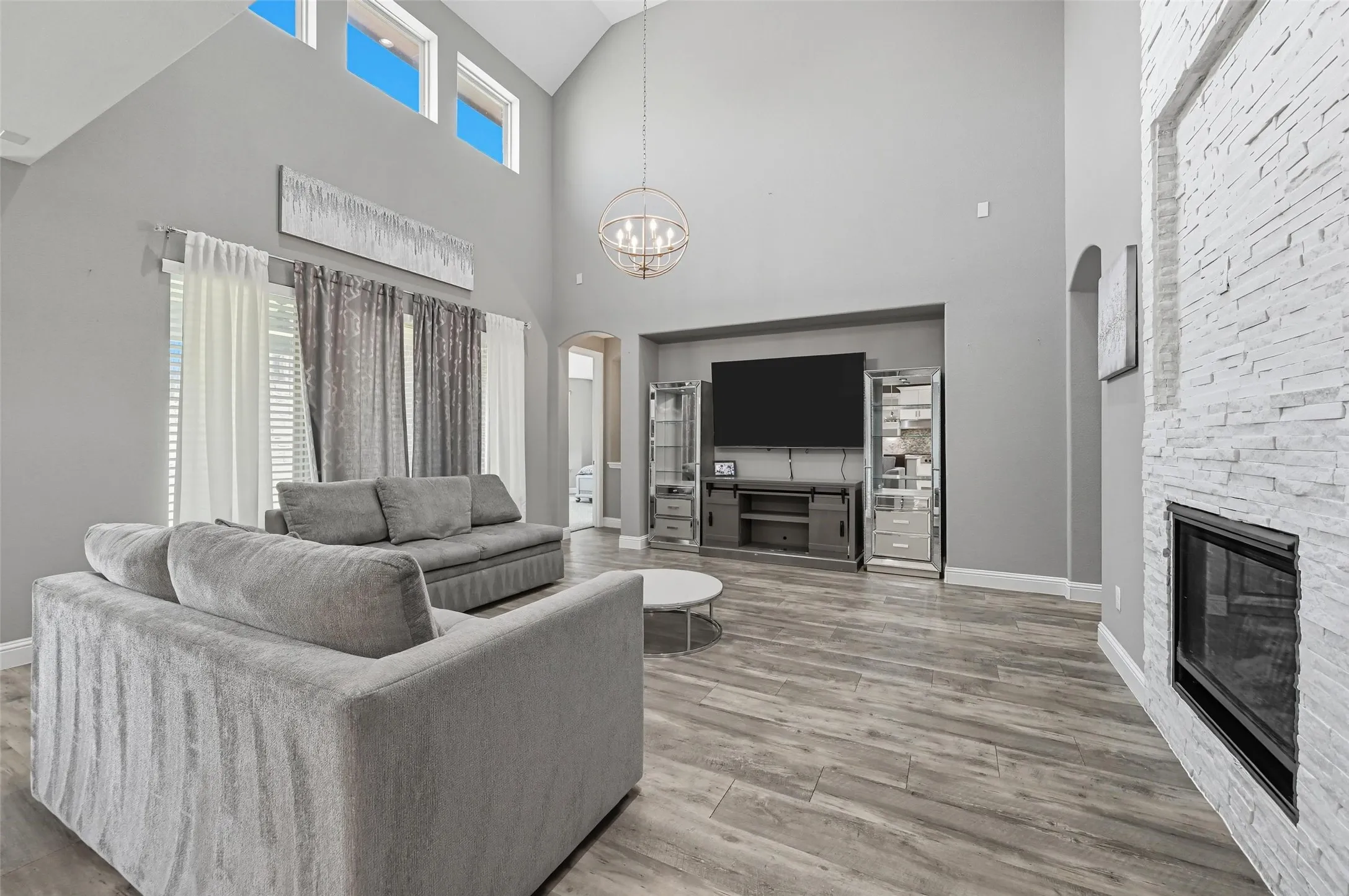 Expansive living space featuring high vaulted ceilings, multiple transom windows, and wood-finish flooring