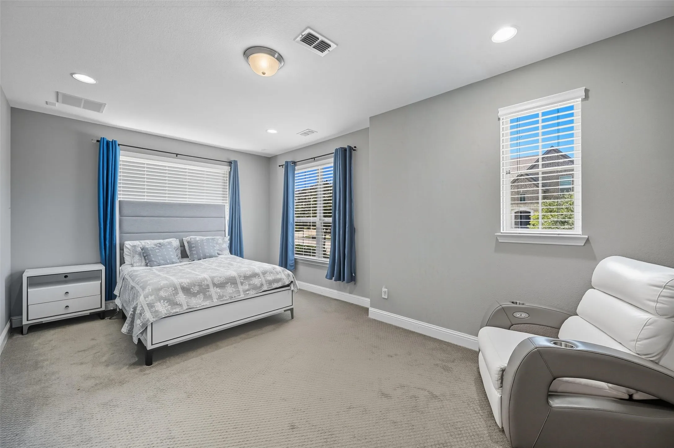 Carpeted room featuring multiple windows with blinds, recessed lighting, and a central ceiling light fixture