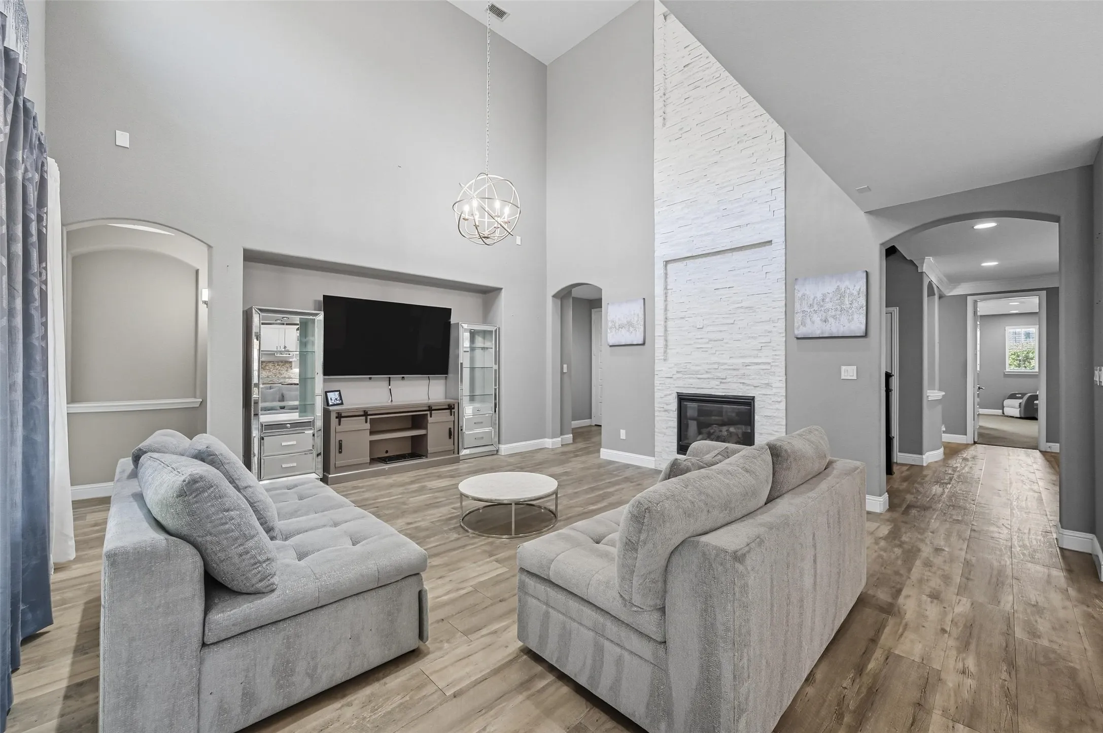Living space featuring vaulted ceilings, wood-finish flooring, and a contemporary spherical chandelier