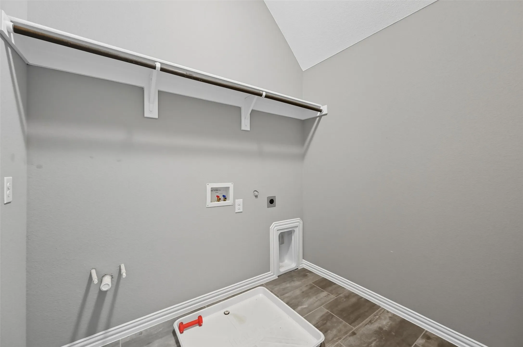 Utility room featuring tiled flooring, a built-in hanging rod, plumbing for washing machine, and dryer vent hookup
