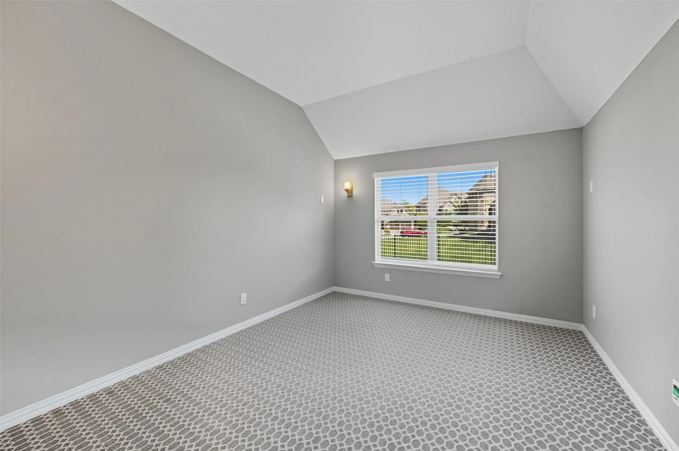 Room featuring a vaulted ceiling and a pattern-textured carpet