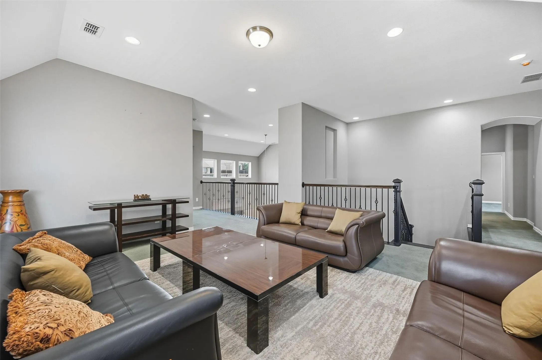 Spacious open-concept room featuring vaulted ceilings, recessed lighting, and light gray wall tones