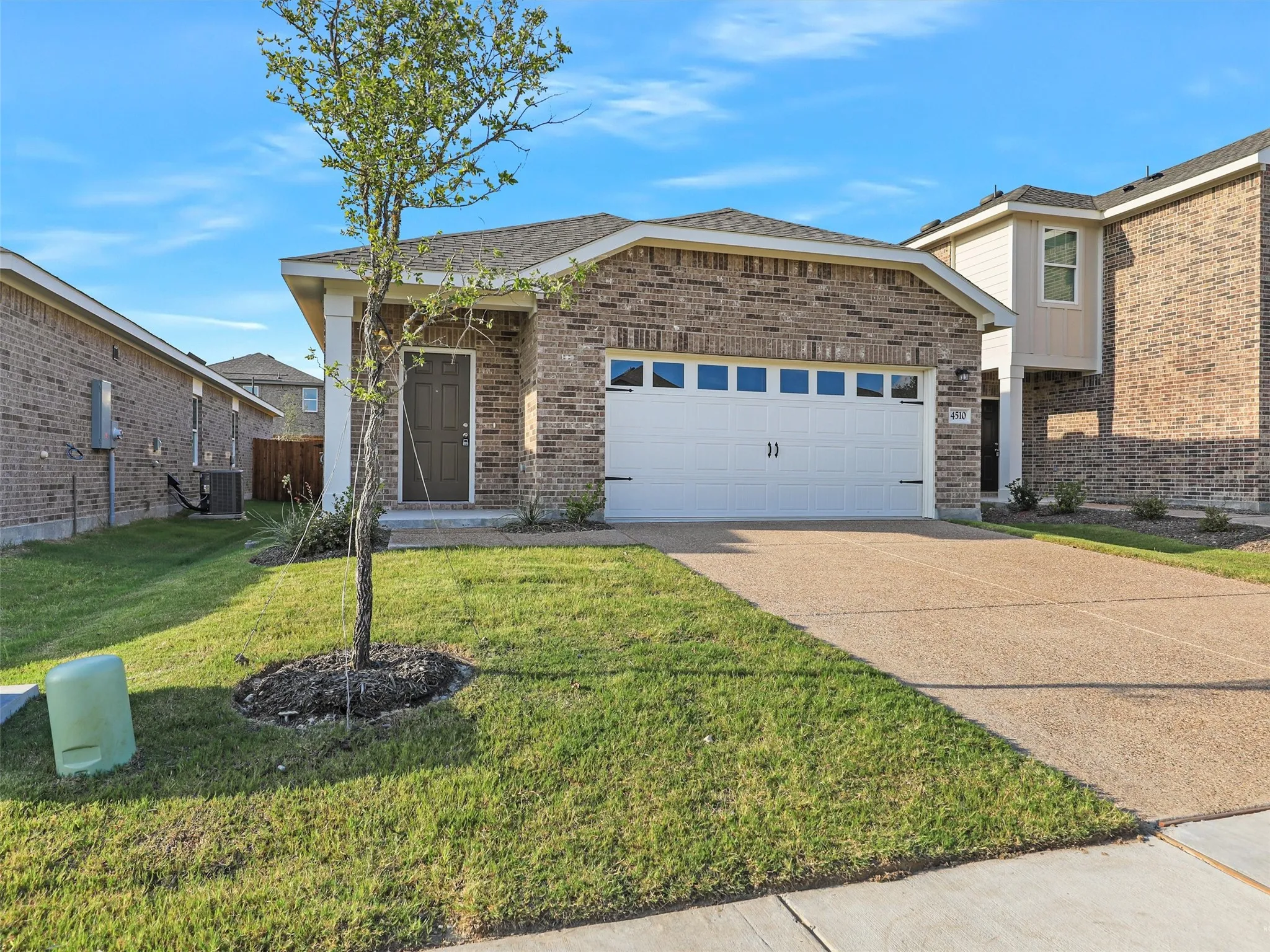 Brick exterior with a prominent two-car garage featuring a white door with window accents