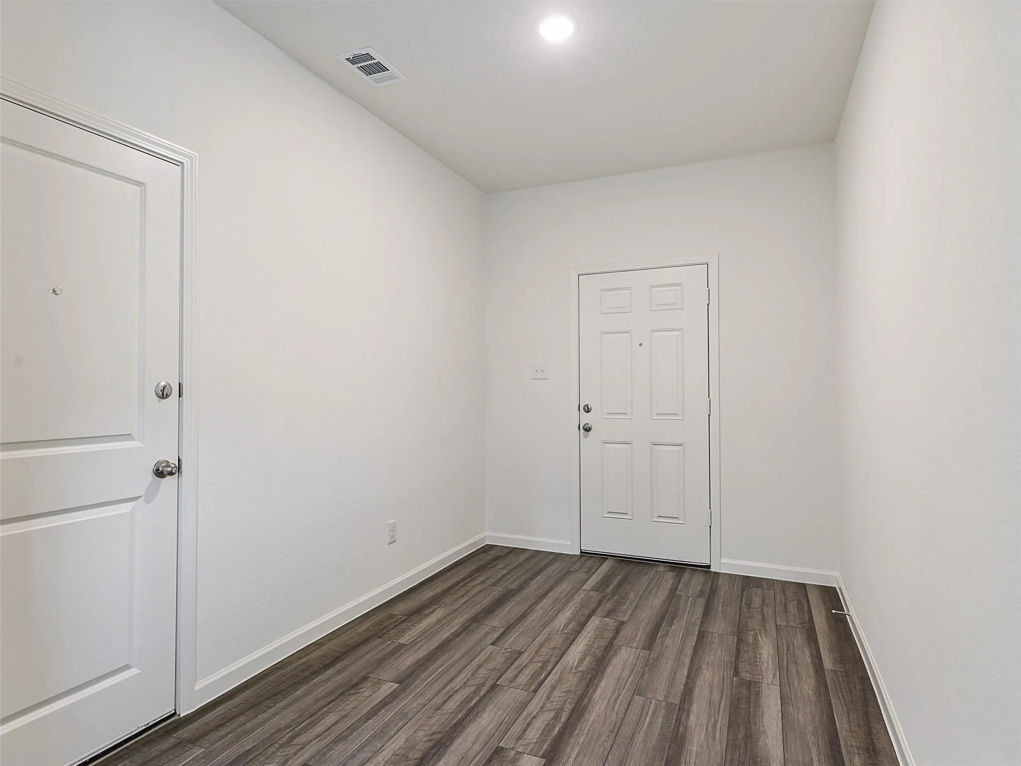 Entryway featuring wood-finish flooring, crisp white walls, and bright overhead lighting