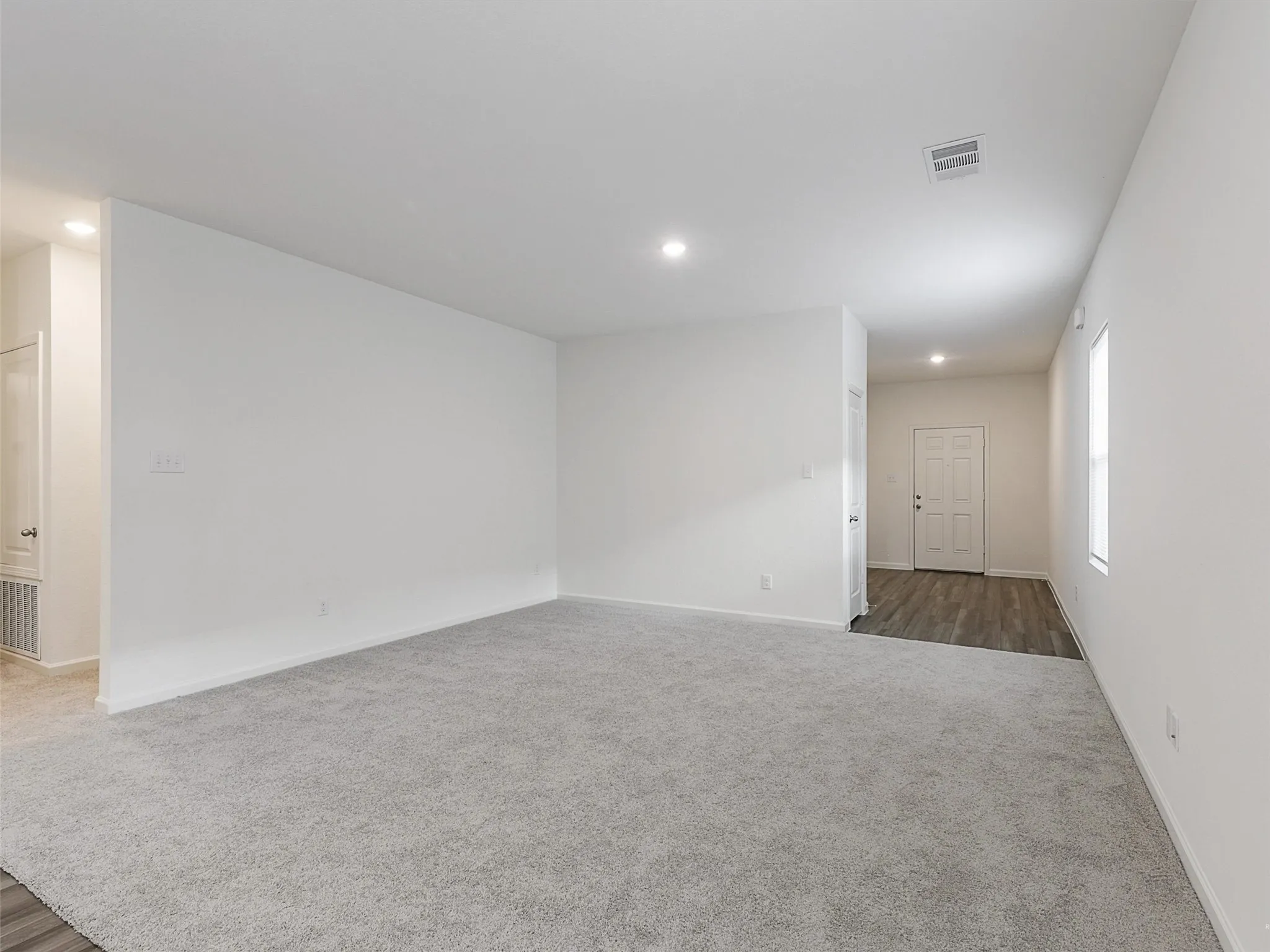 Spacious room featuring gray carpeting, white walls, recessed lighting, and a white ceiling