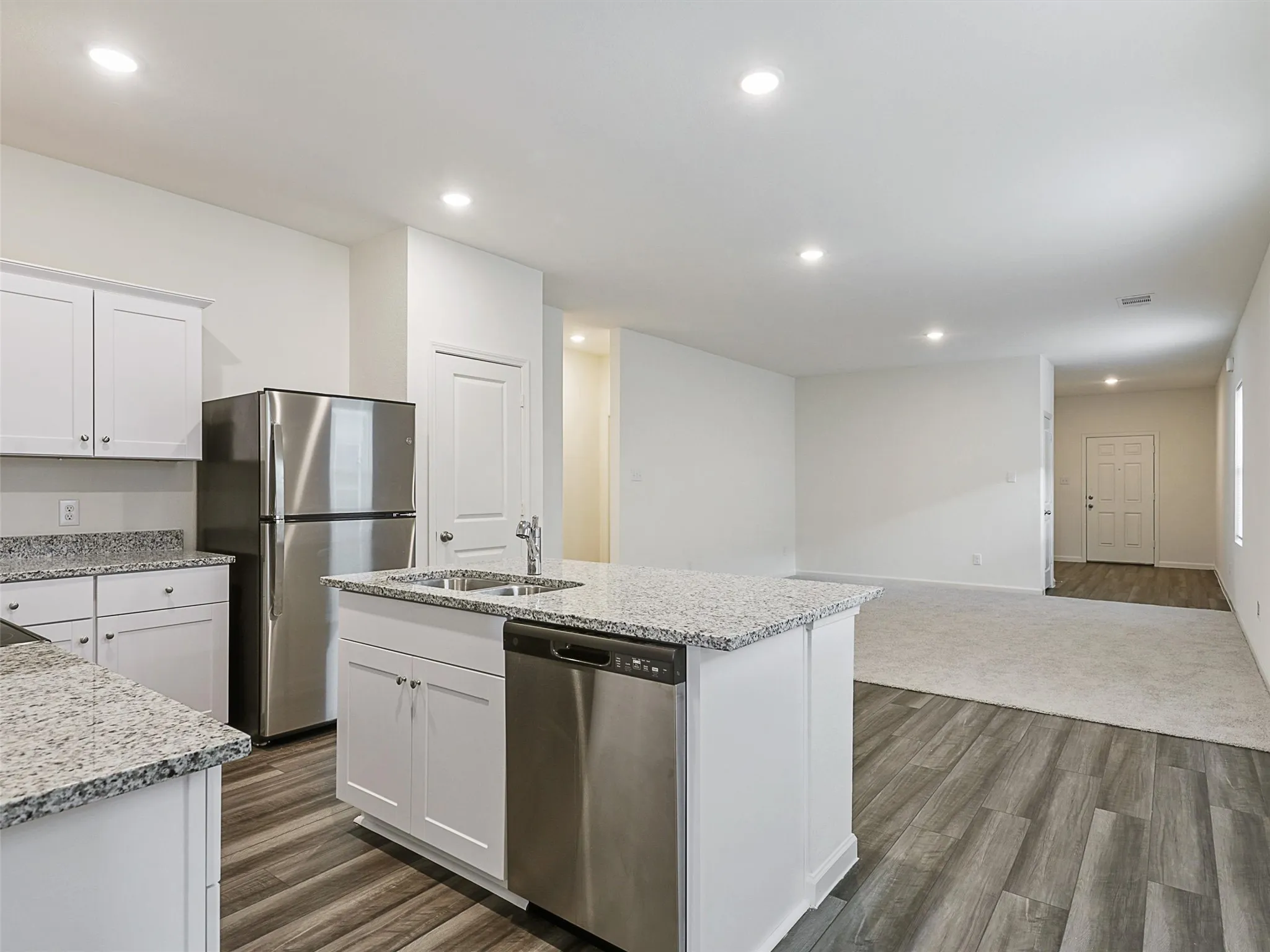 Kitchen featuring wood-finish flooring, white cabinetry, granite countertops, and stainless steel appliances including a refrigerator and dishwasher