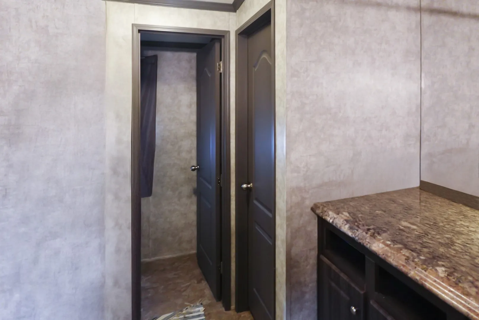 Paneling walls with wood-finish trim, dark wood-finish interior doors, and a built-in vanity with a stone-look countertop and dark cabinetry
