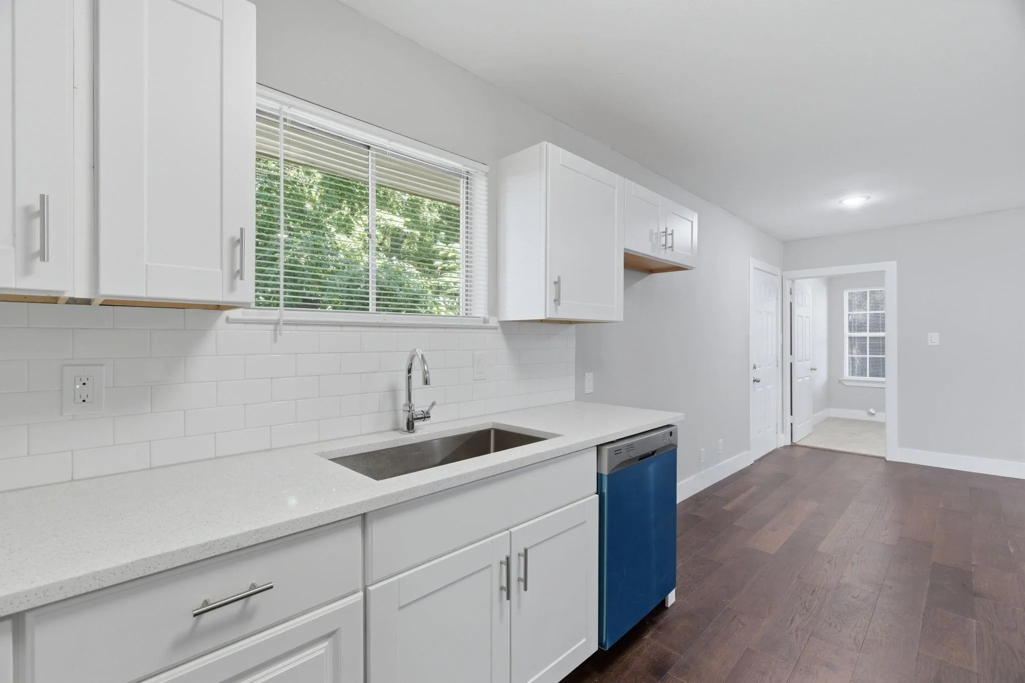 Kitchen featuring white shaker cabinetry, light-colored countertops, and a subway tile backsplash
