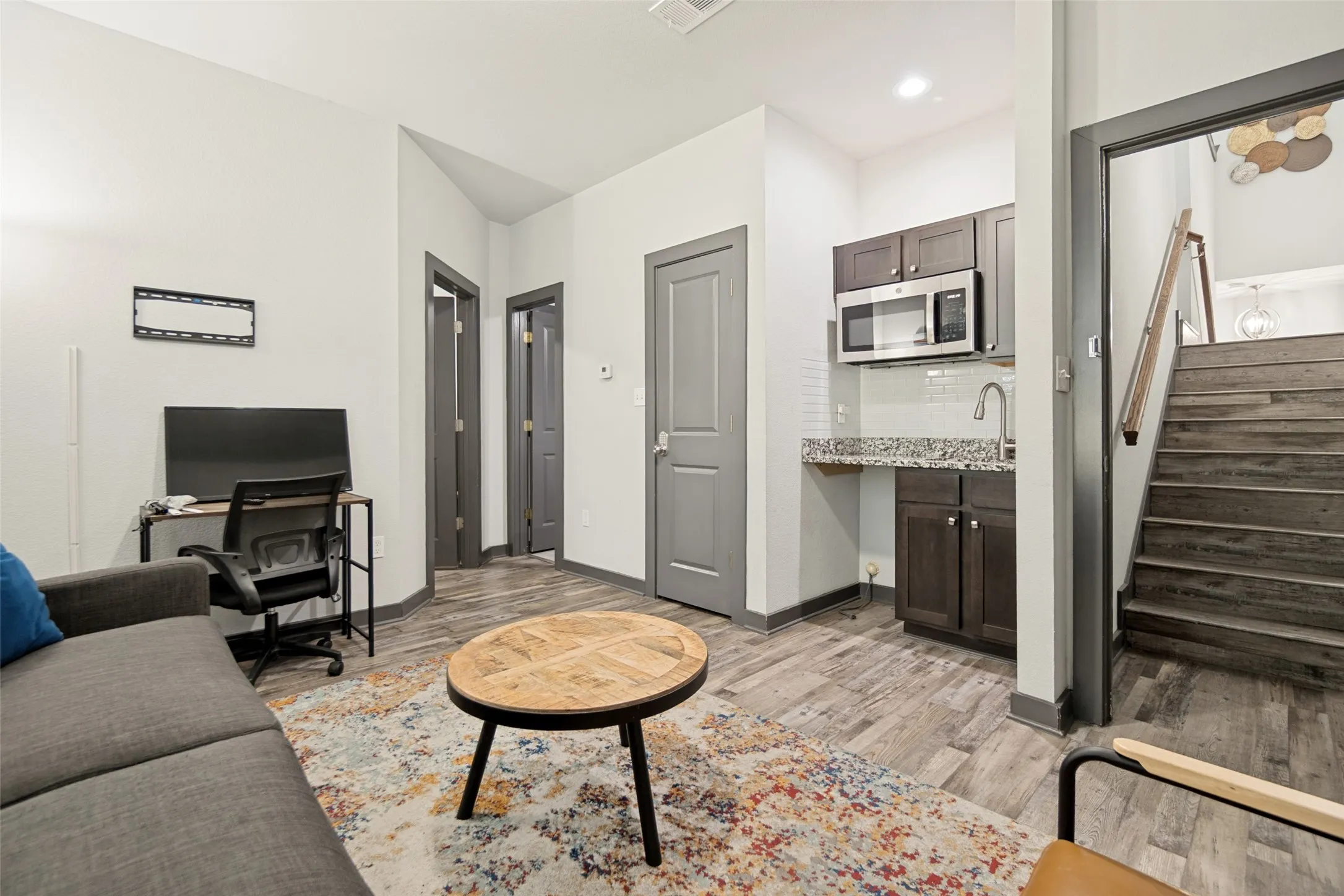 Modern open-concept living area featuring wood-finish flooring, neutral wall finishes, and recessed lighting throughout