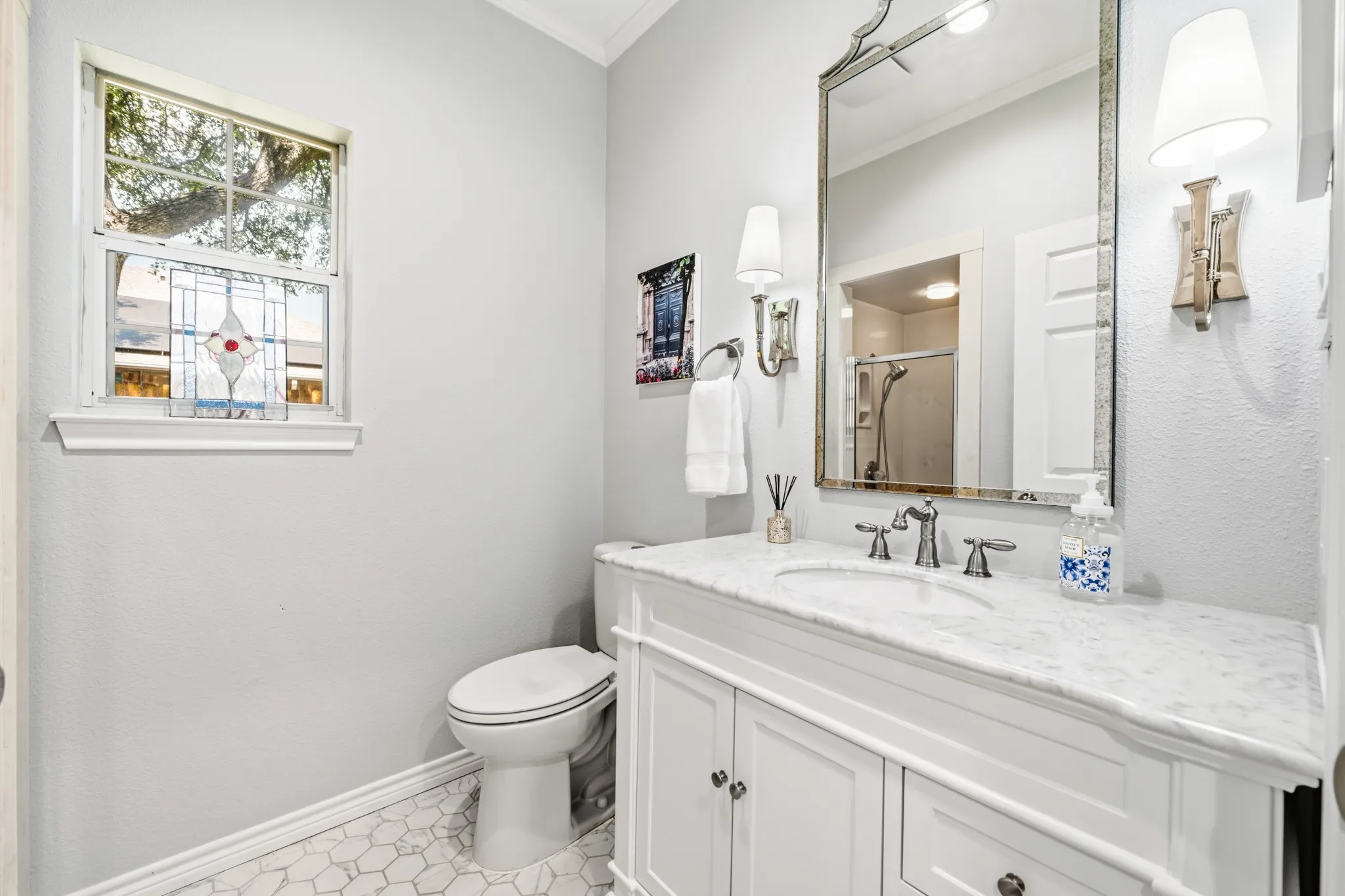 Pristine & Pretty Guest Bath!  Quaint octagon tiled floors, show-stopper sconces, & charming vanity