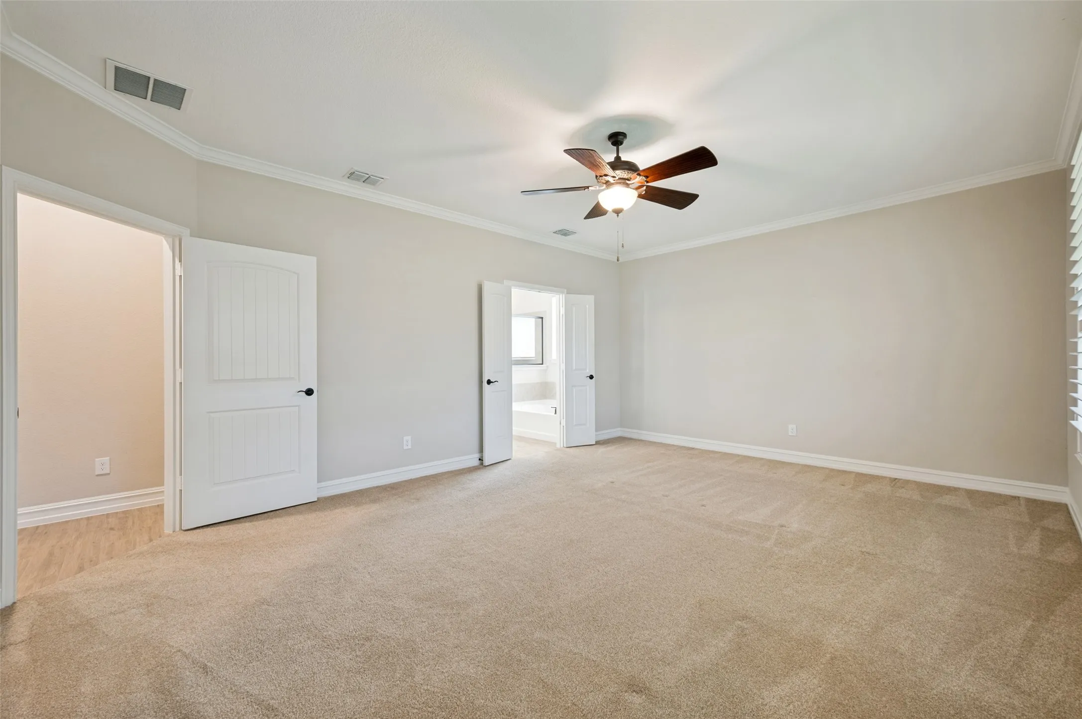 Spacious room featuring neutral carpeting, light-toned walls, and white crown molding
