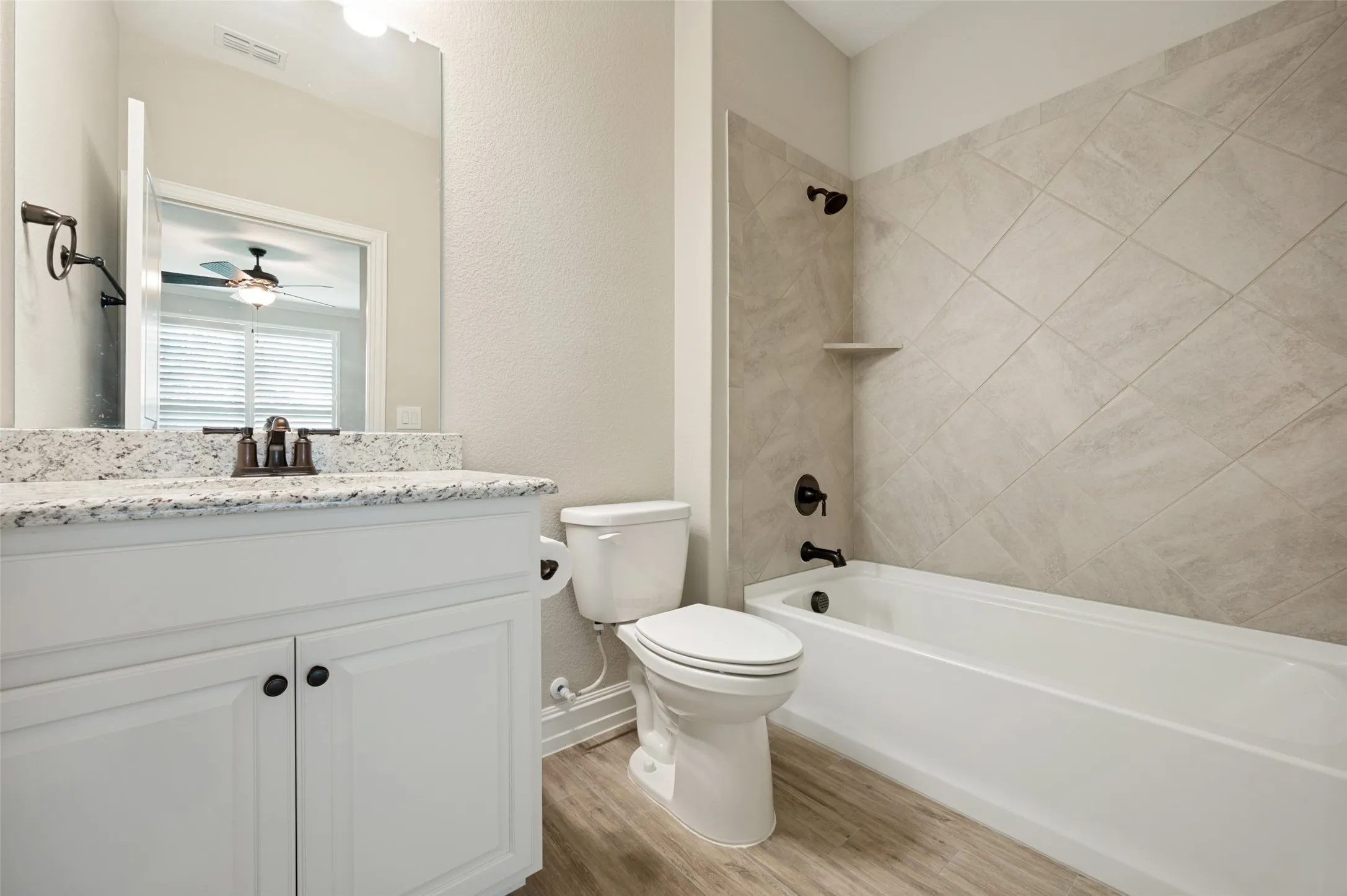 Spa-inspired bathroom featuring a white vanity with shaker-style cabinetry, granite countertop, and oil-rubbed bronze fixtures