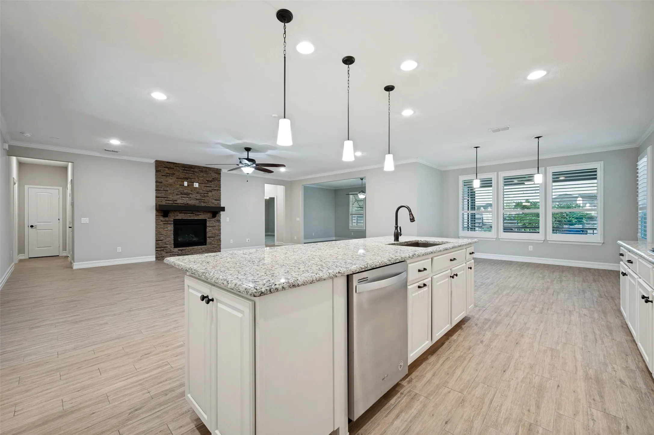 Gourmet kitchen featuring a large center island with quartz countertop and stainless steel appliances, white cabinetry, pendant lighting, recessed ceiling fixtures, ceiling fan, and wood-finish flooring throughout