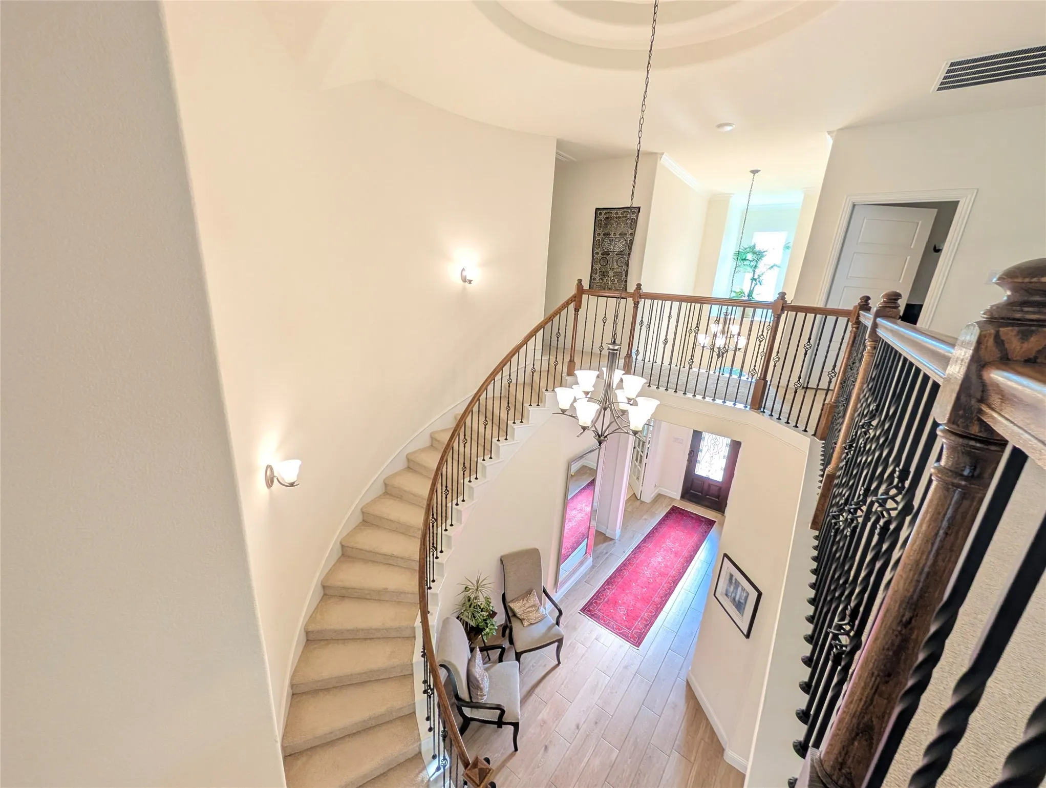 Grand foyer with a curved staircase featuring wrought iron balusters and wood handrails
