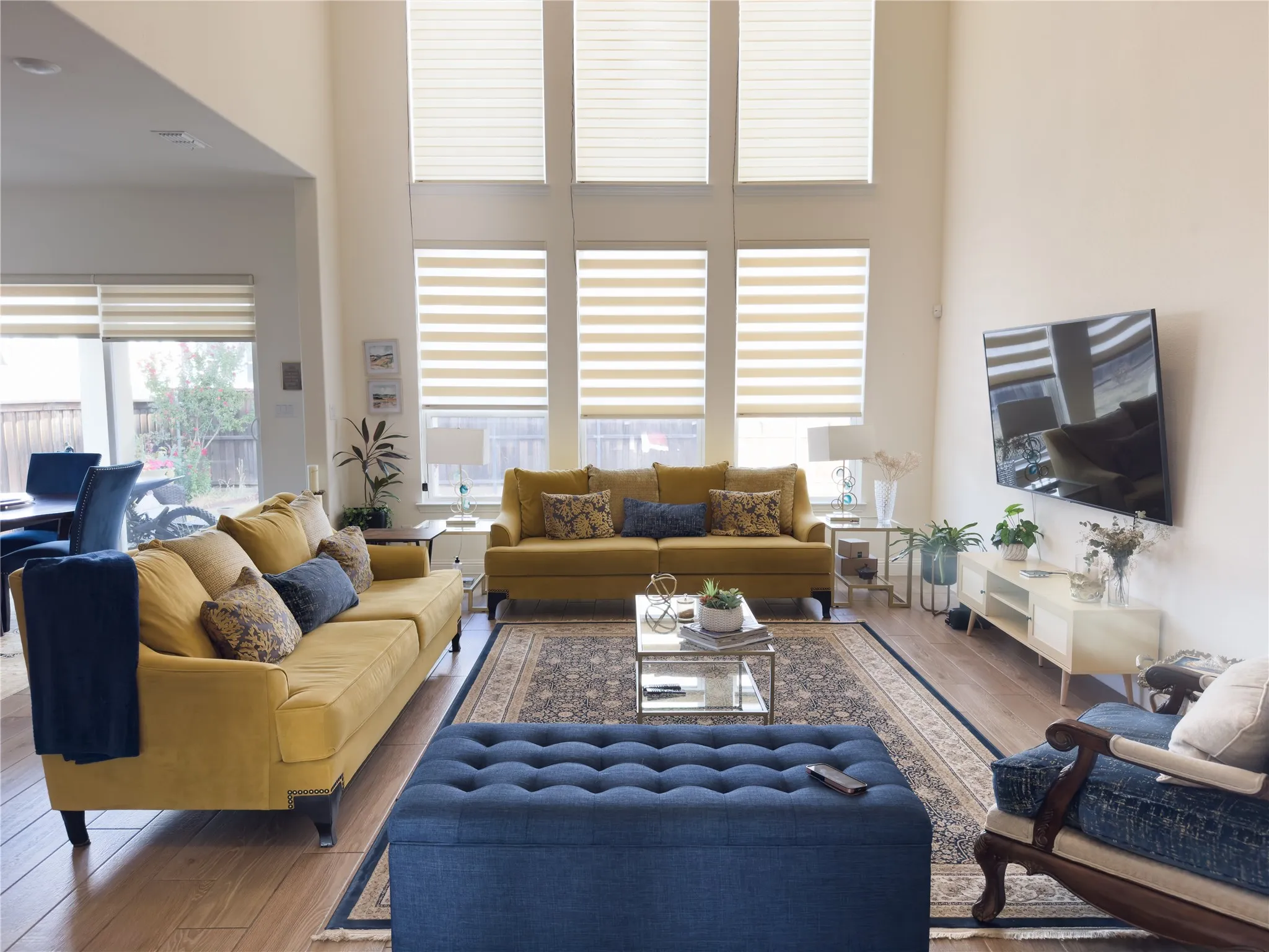 Double-height ceilings, wood-finish flooring, multiple expansive windows, built-in wall-mounted television, and a built-in media console