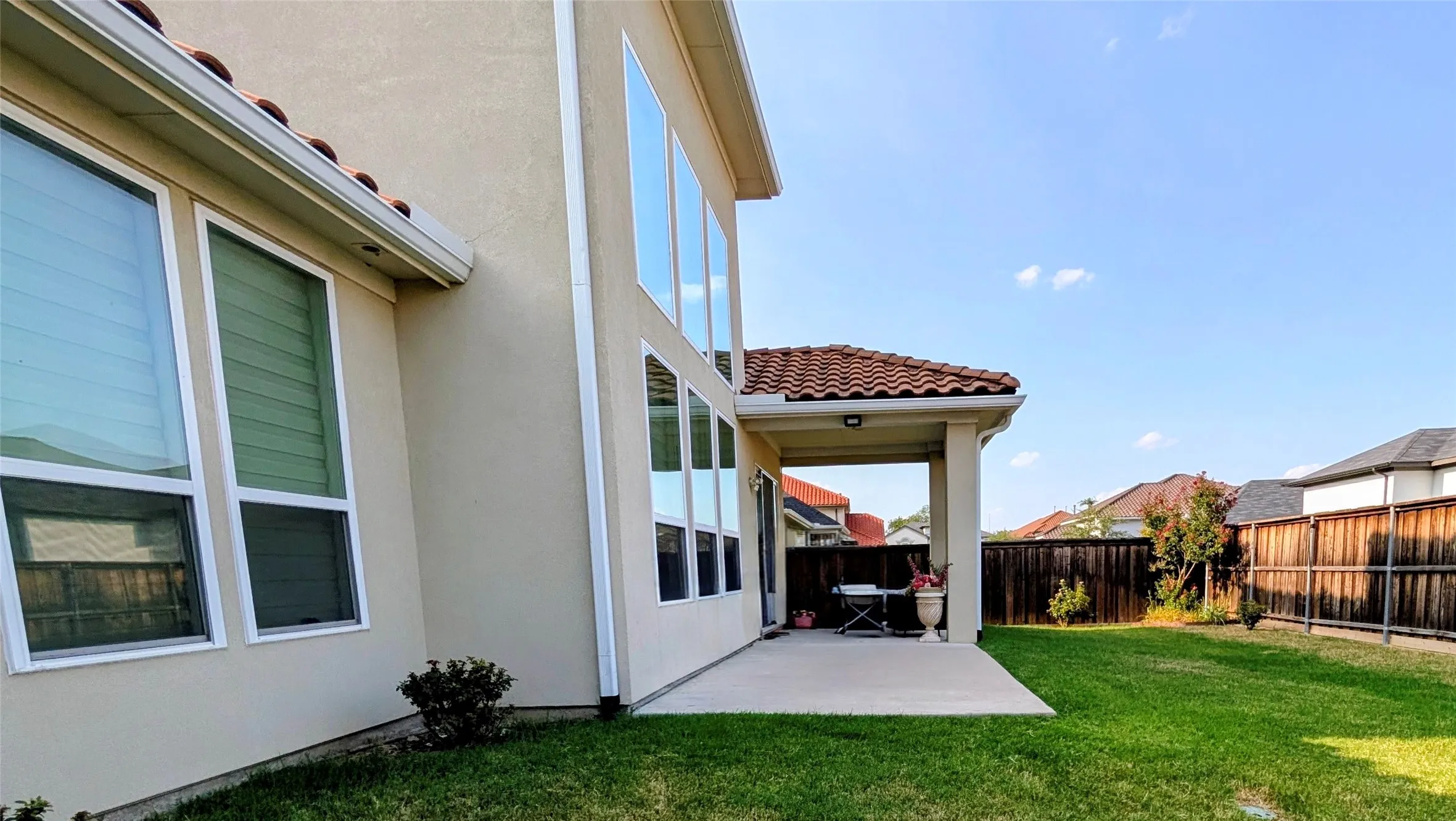 Rear exterior featuring a covered patio with recessed lighting, stucco siding, a terracotta tile roof, and multiple large windows