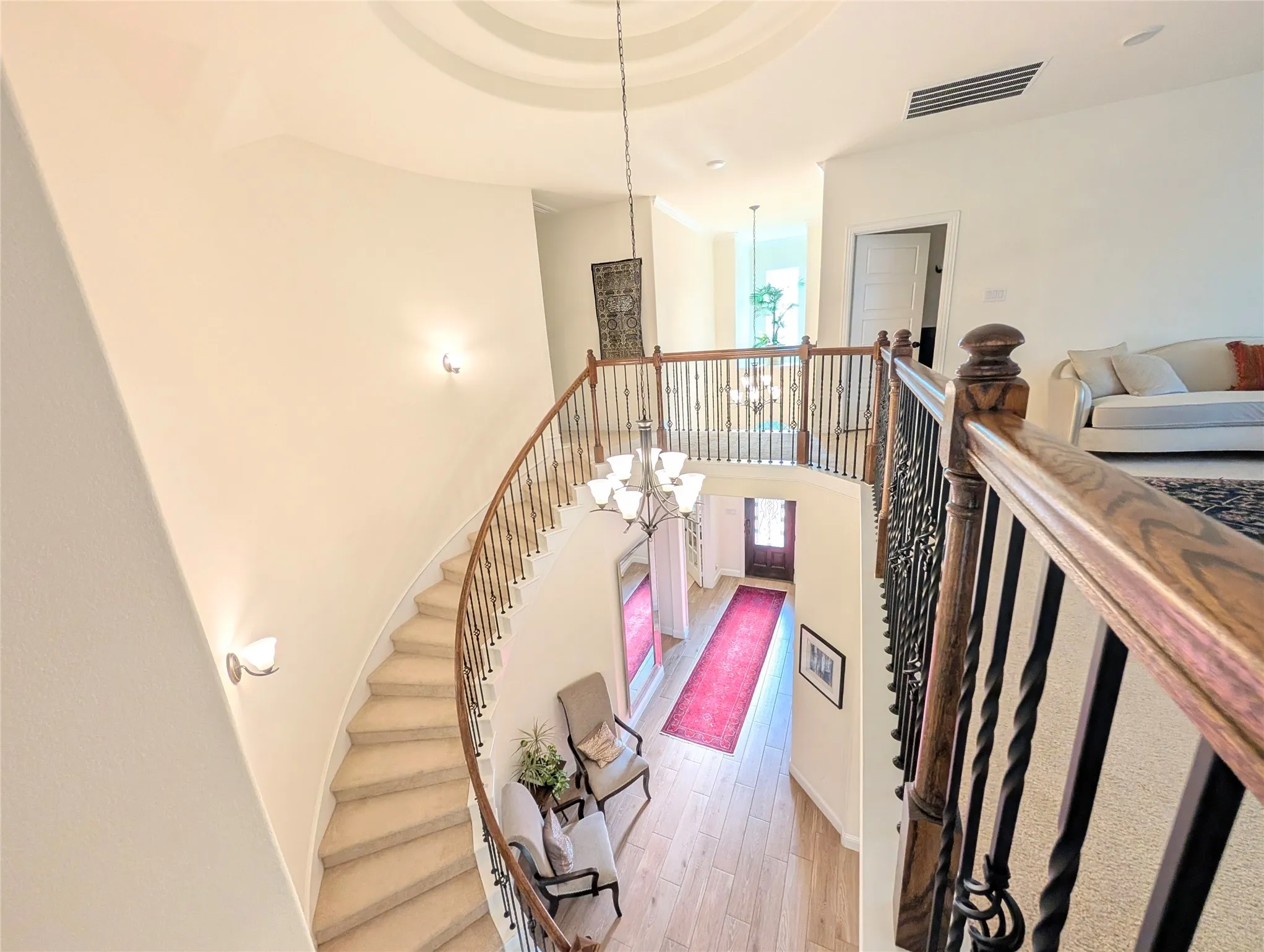 Sweeping curved staircase with carpeted treads and a dark wood handrail