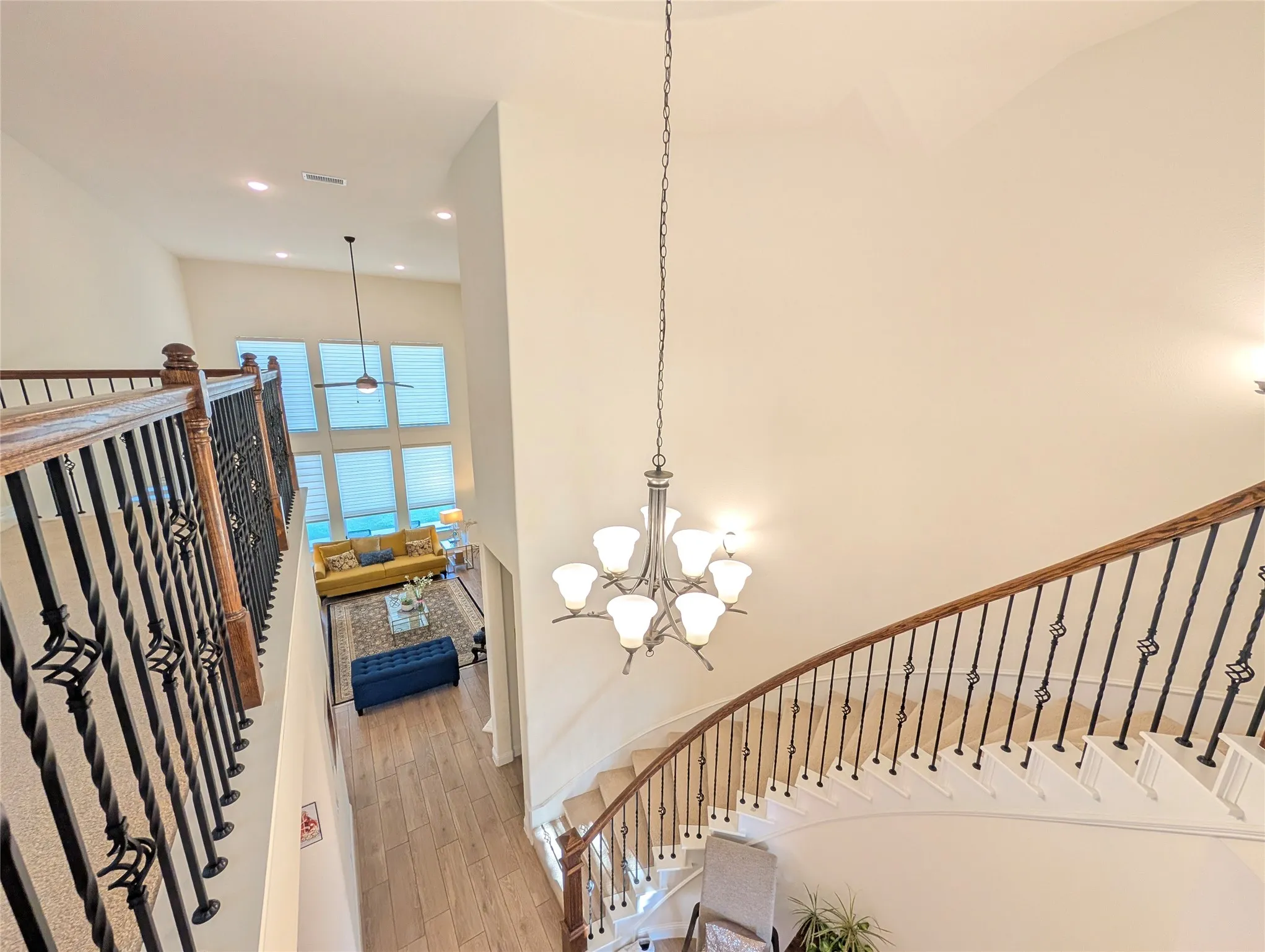 Double-height foyer featuring a curved staircase with wood banister and wrought iron spindles, a multi-tier chandelier, and recessed lighting