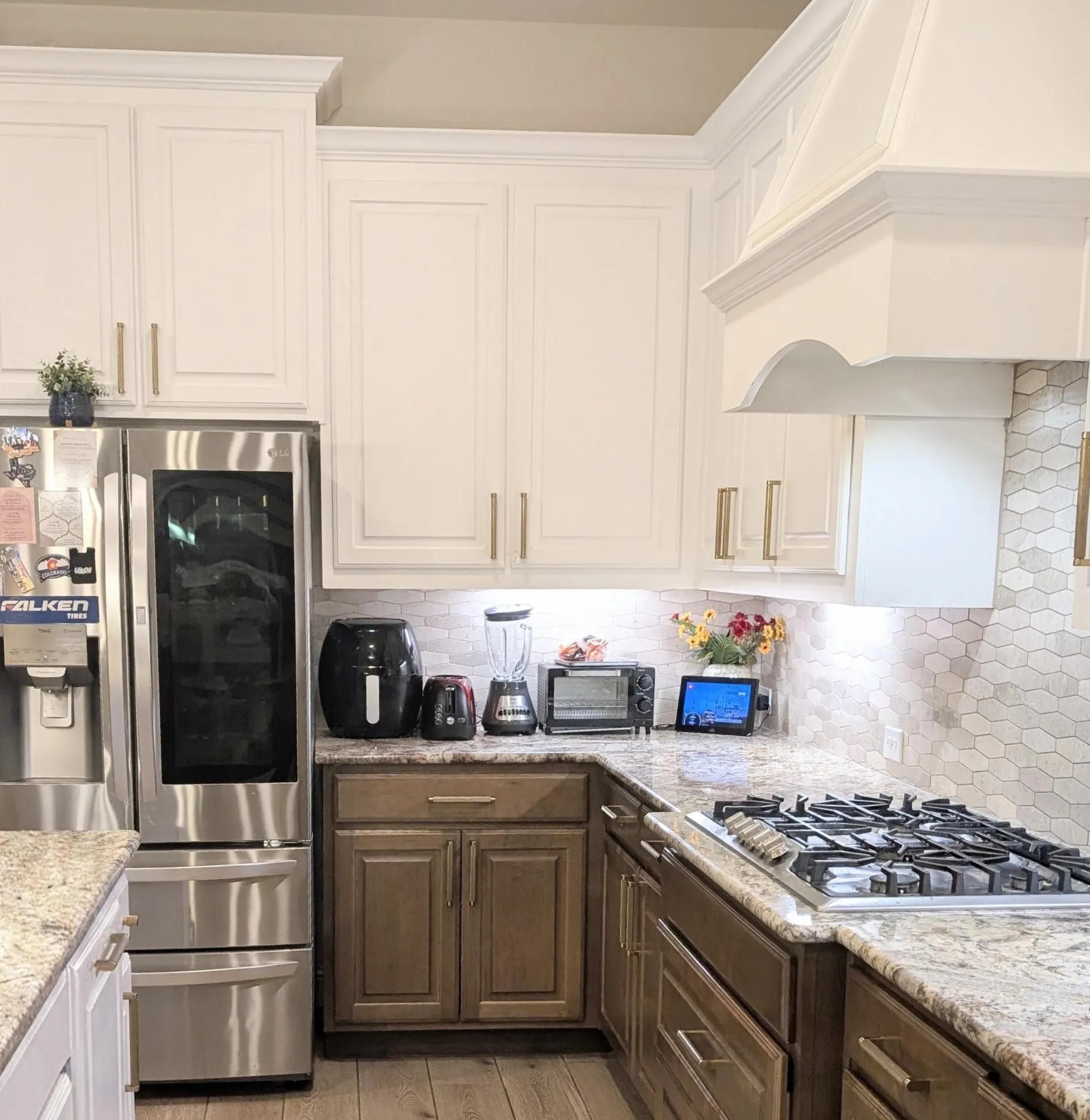 Chef's kitchen featuring custom cabinetry with brushed nickel hardware, quartz countertops, subway tile backsplash, stainless steel appliances including a six-burner gas cooktop, and a built-in range hood