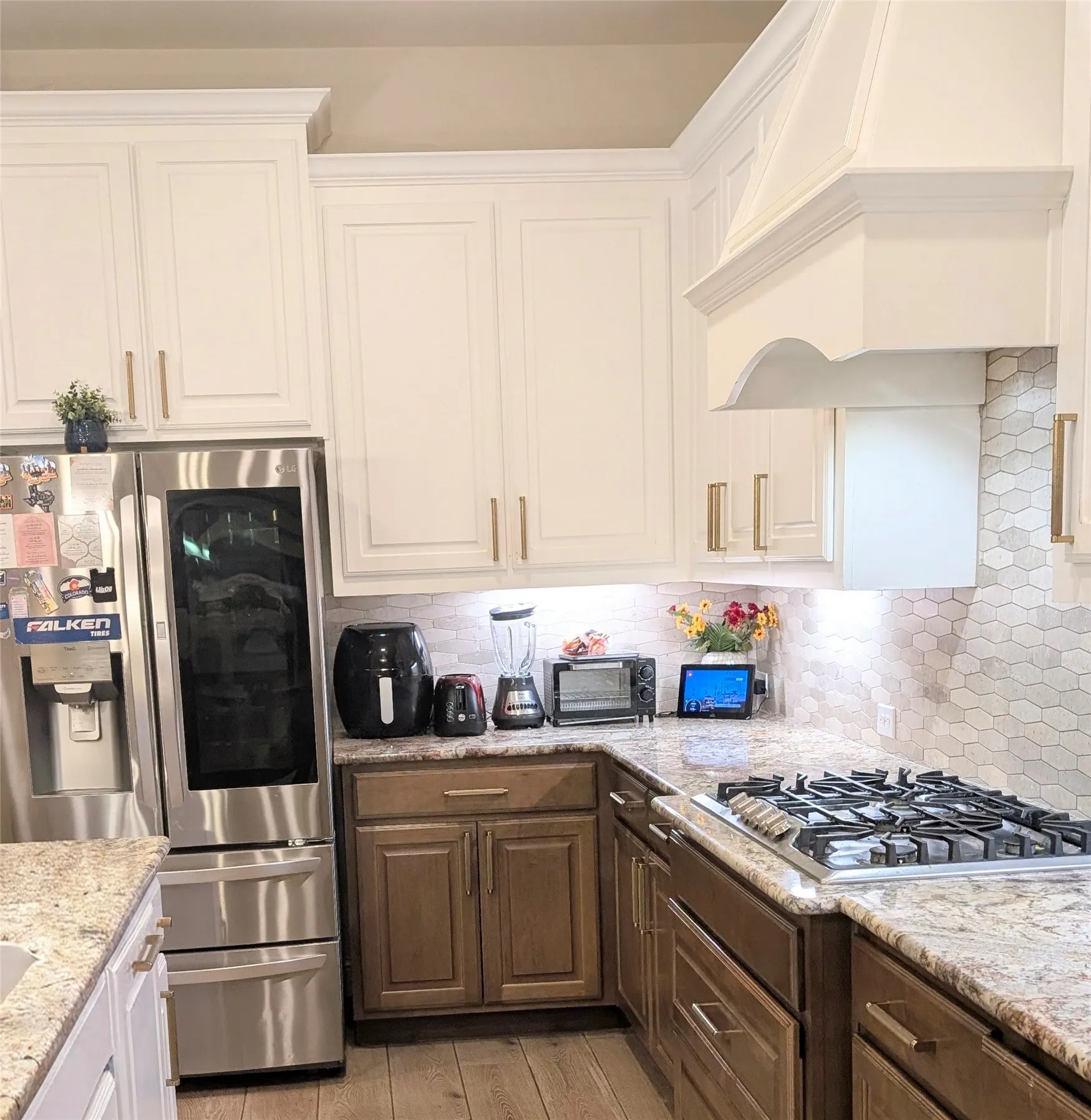 Kitchen featuring upper white cabinetry and lower wood-finish cabinetry, granite countertops, and a gas cooktop