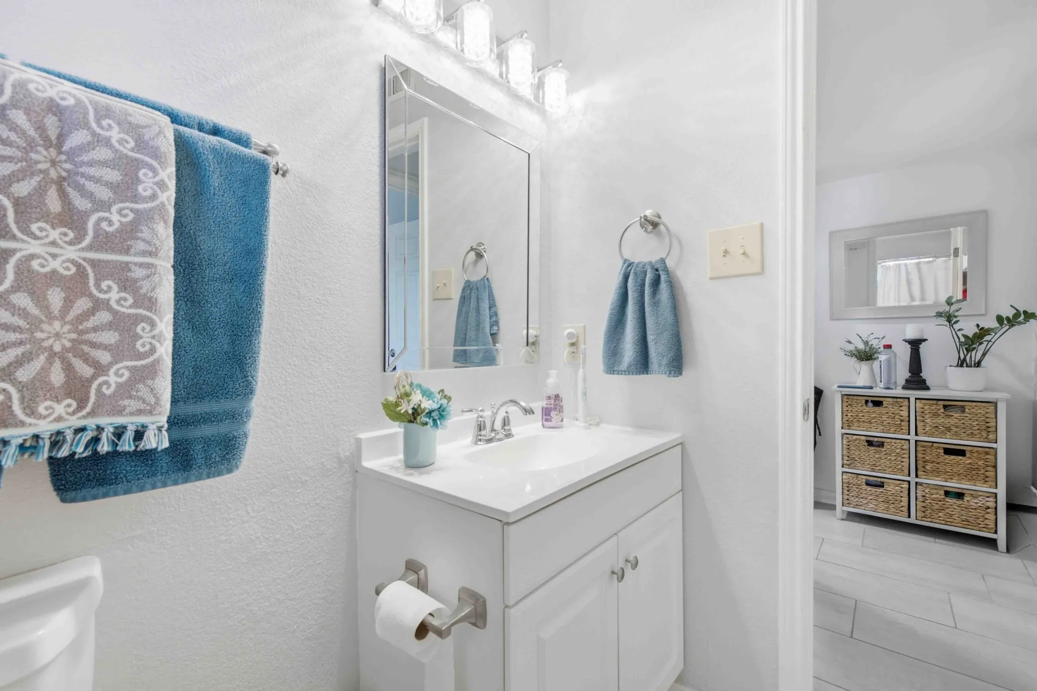 White vanity with a single basin, chrome faucet, and storage cabinetry