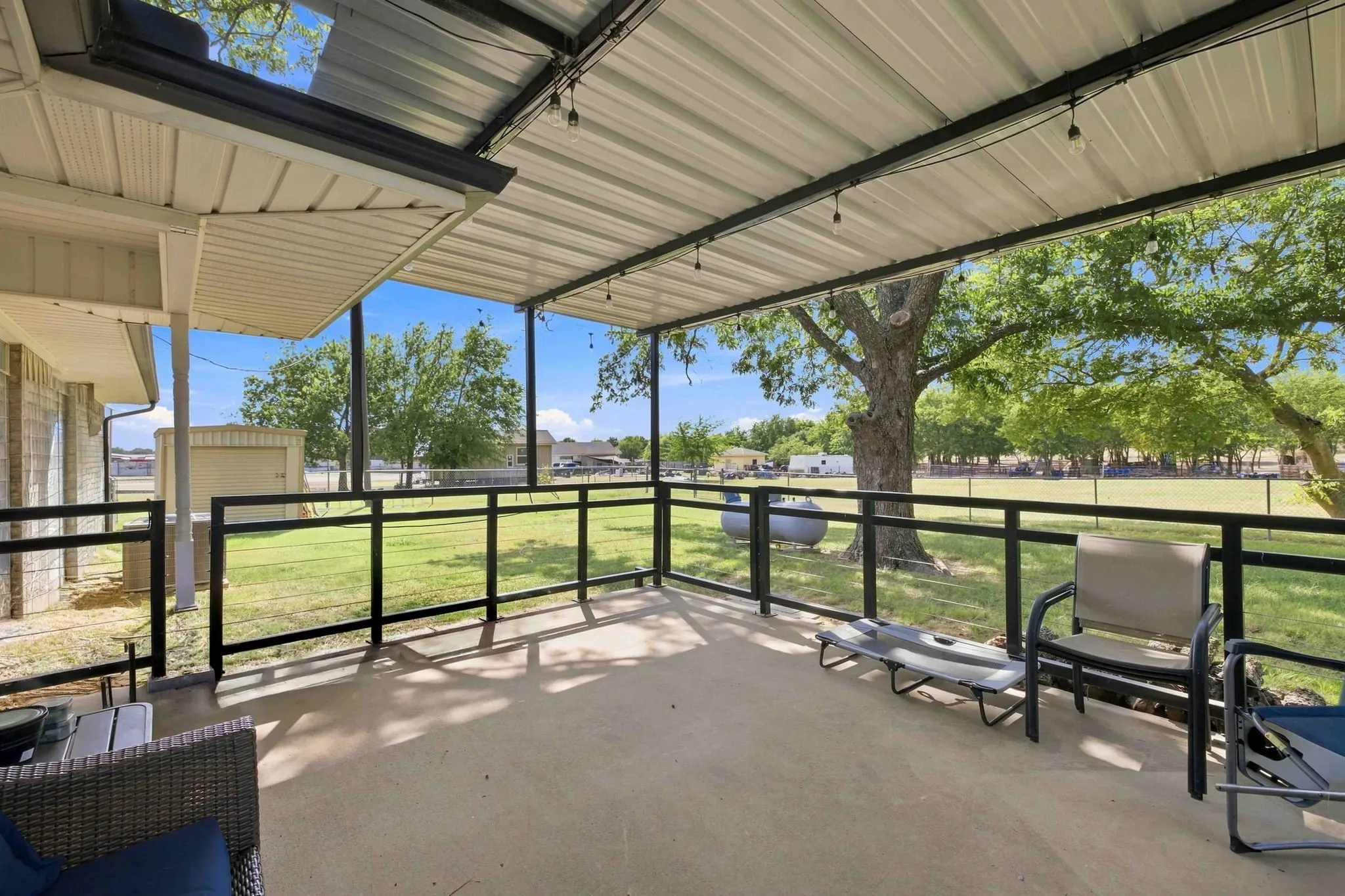 Covered concrete patio with a metal roof and open-air railing