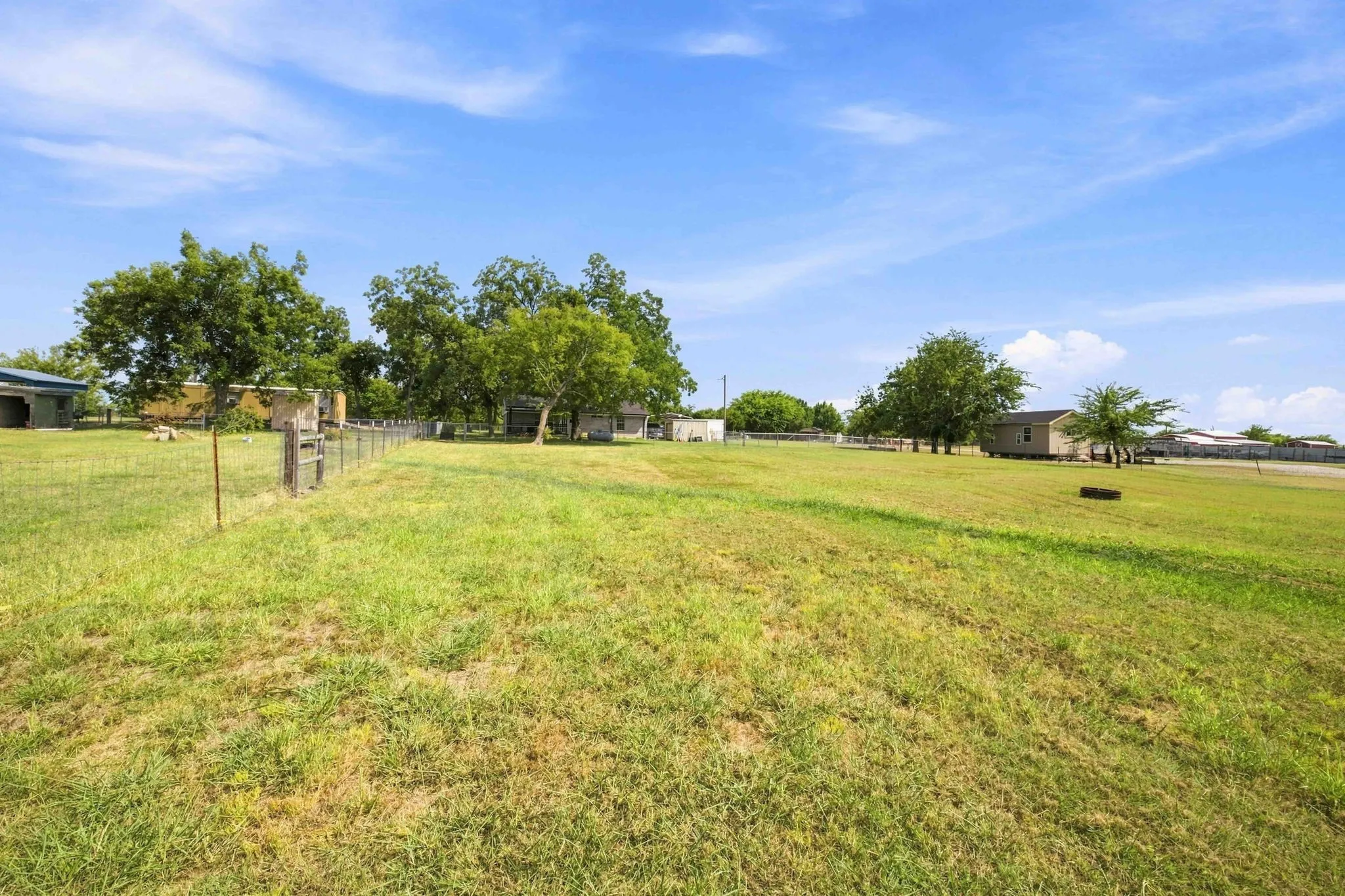 Expansive grassy grounds with mature trees and a perimeter fence