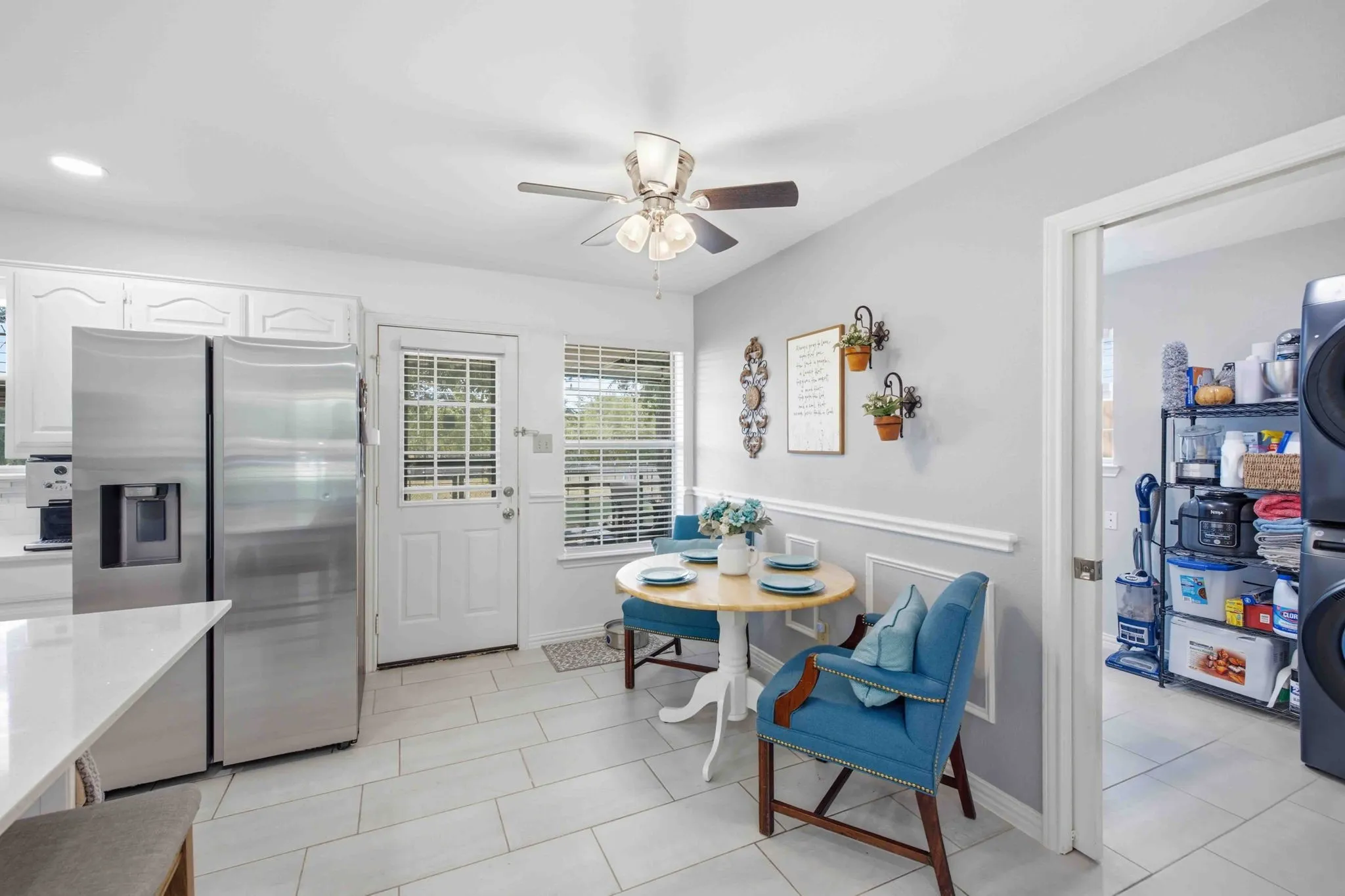 Kitchen with white cabinetry, stainless steel refrigerator, and light tile flooring