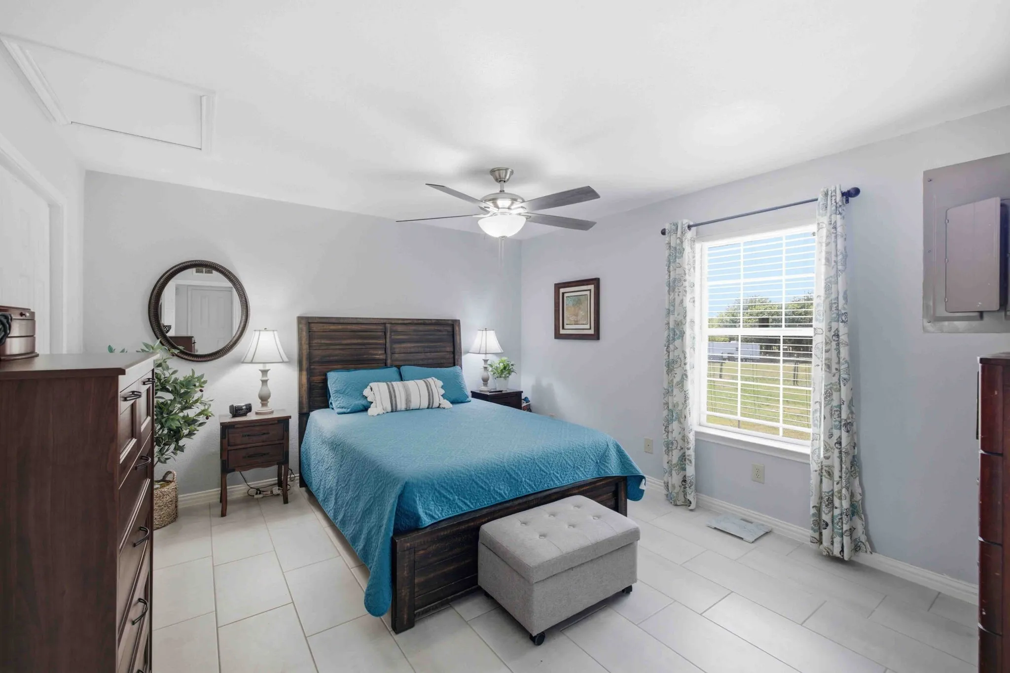 Spacious room featuring light-colored tile flooring, a large window, and a ceiling fan