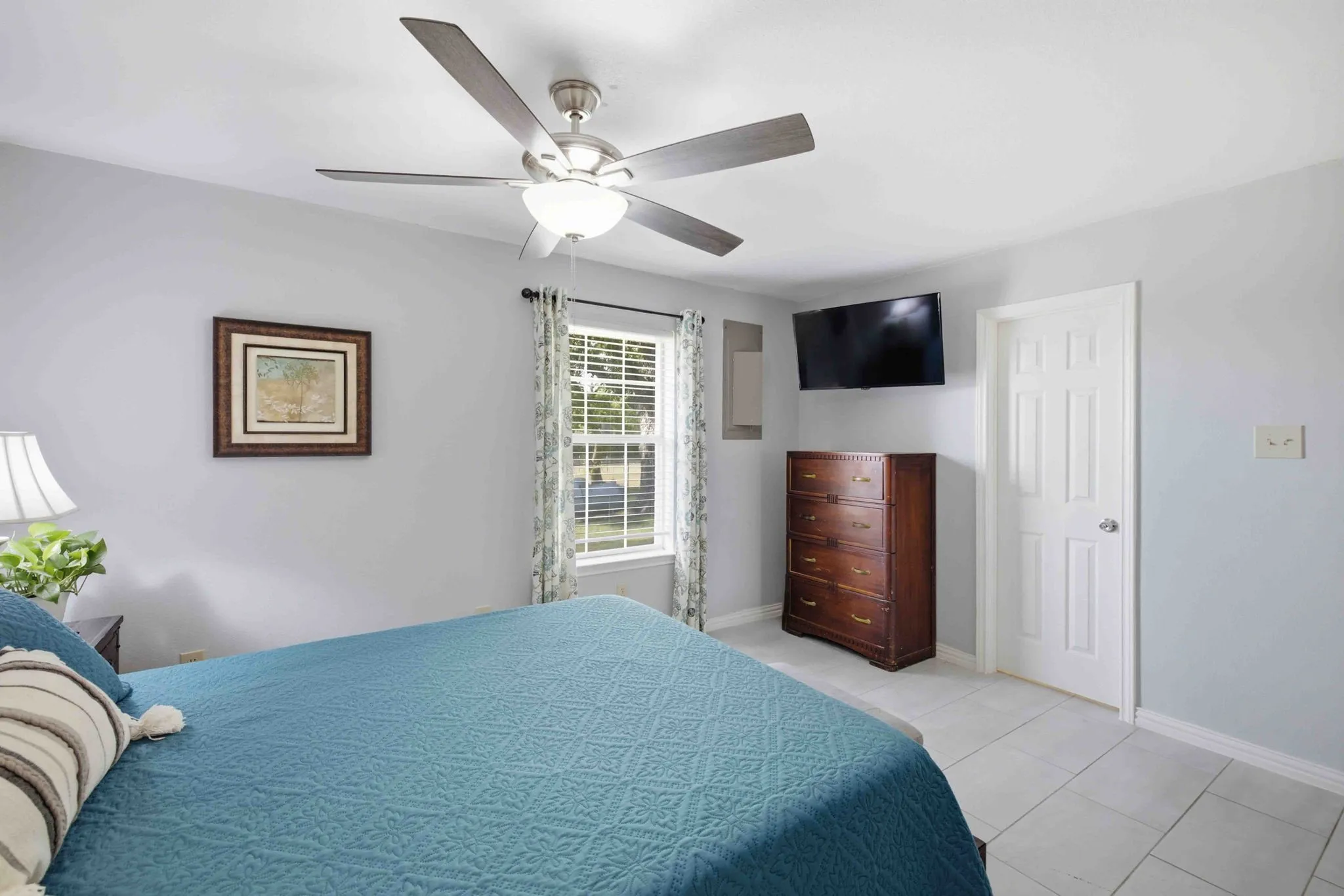 Ceiling fan with integrated lighting, window with blinds, light gray wall paint, white trim, and light-colored tile flooring