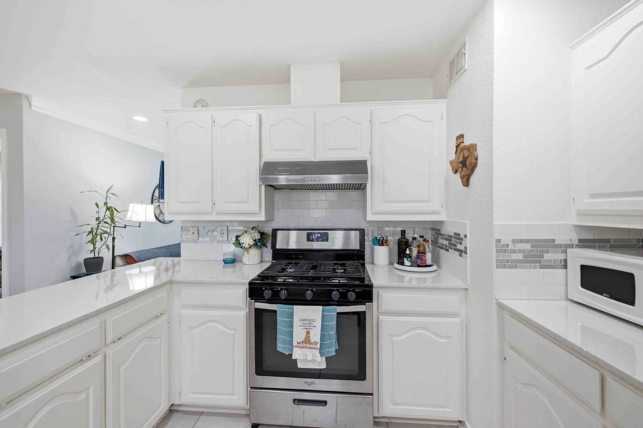 White cabinetry, stainless steel range, white countertops, subway tile backsplash, and mosaic tile accents