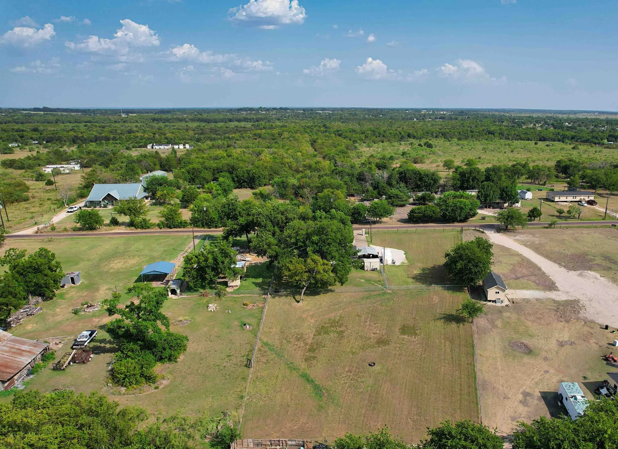 Expansive land parcel featuring multiple structures, open fields, and mature trees