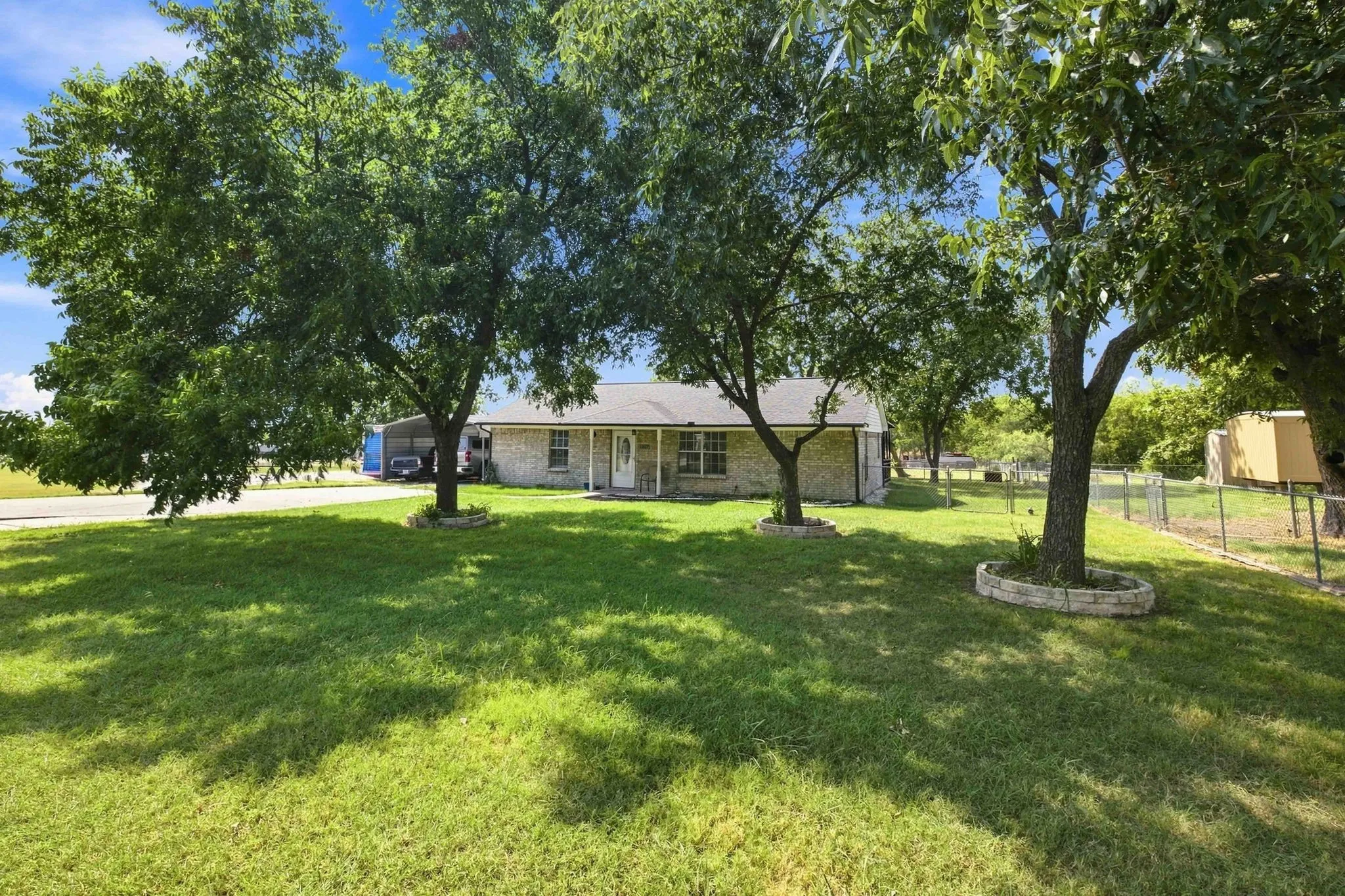 Expansive front lawn with mature trees and stone-edged tree rings
