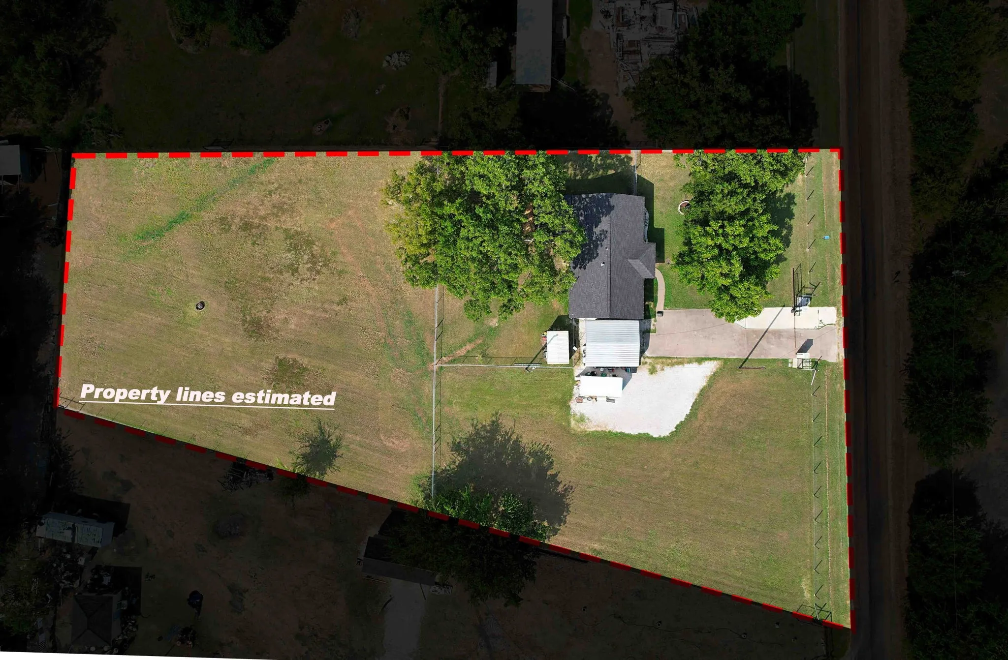 Expansive lot with a single-story residence, asphalt driveway, and mature trees