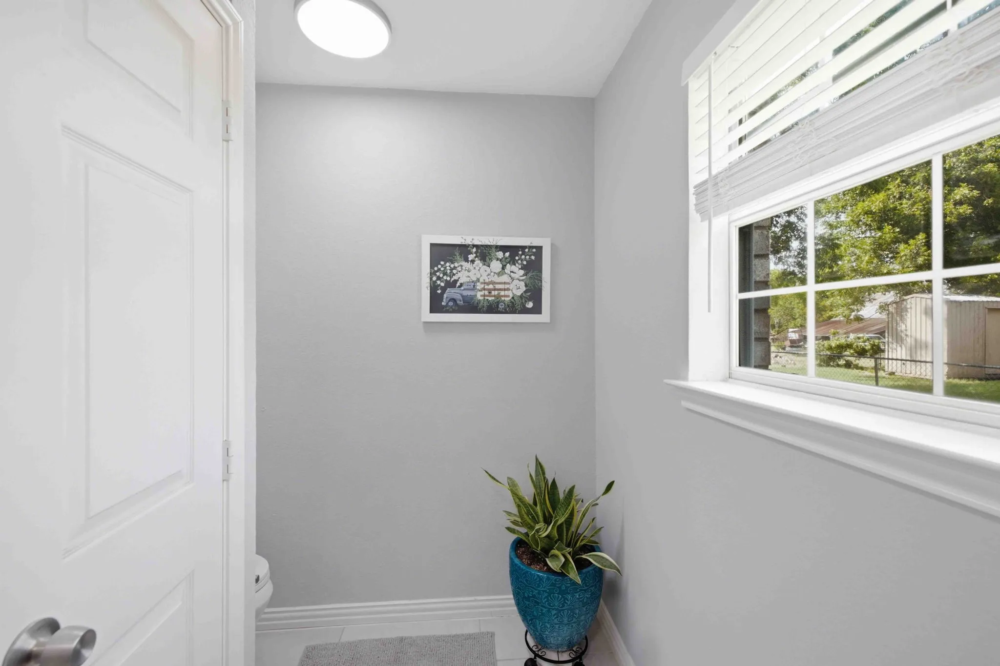 White paneled interior door, window with white blinds, recessed ceiling lighting, and light gray wall paint