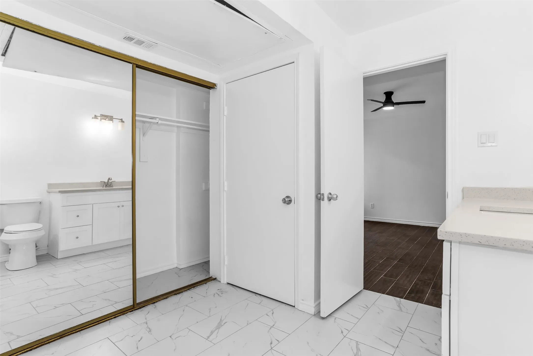 Mirrored sliding closet doors with an interior hanging rod, crisp white walls, and white-finish interior doors