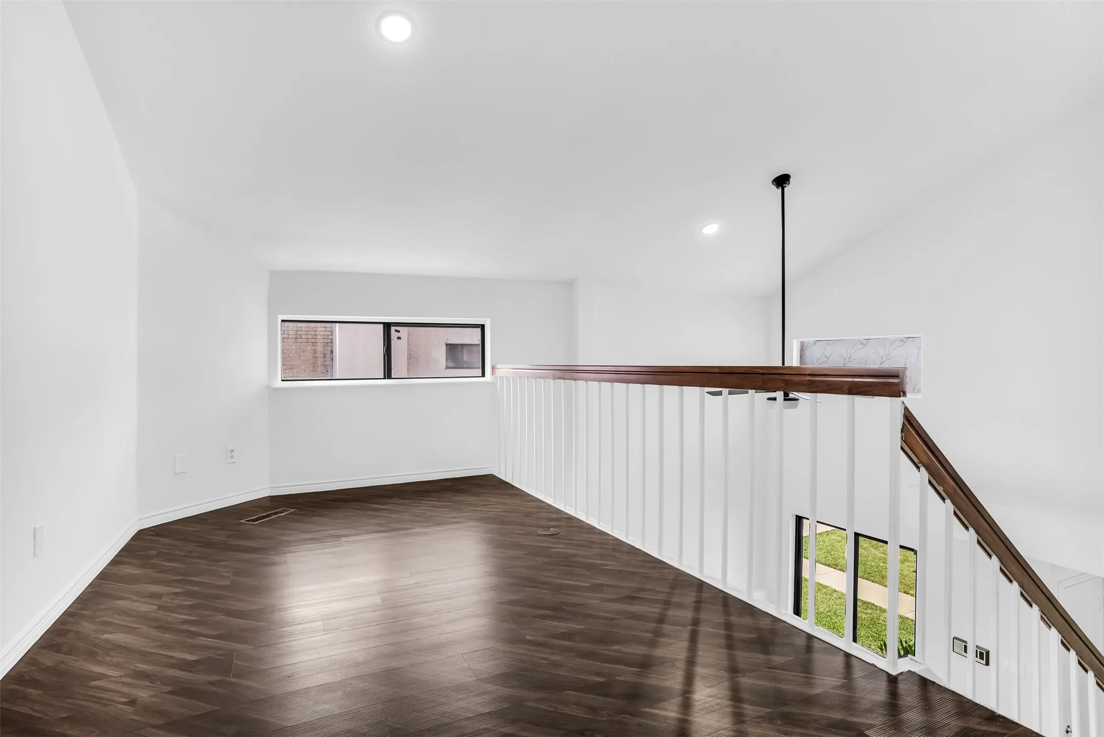 Open loft area featuring wood-finish flooring, recessed lighting, and a white railing with a wood-finish top rail