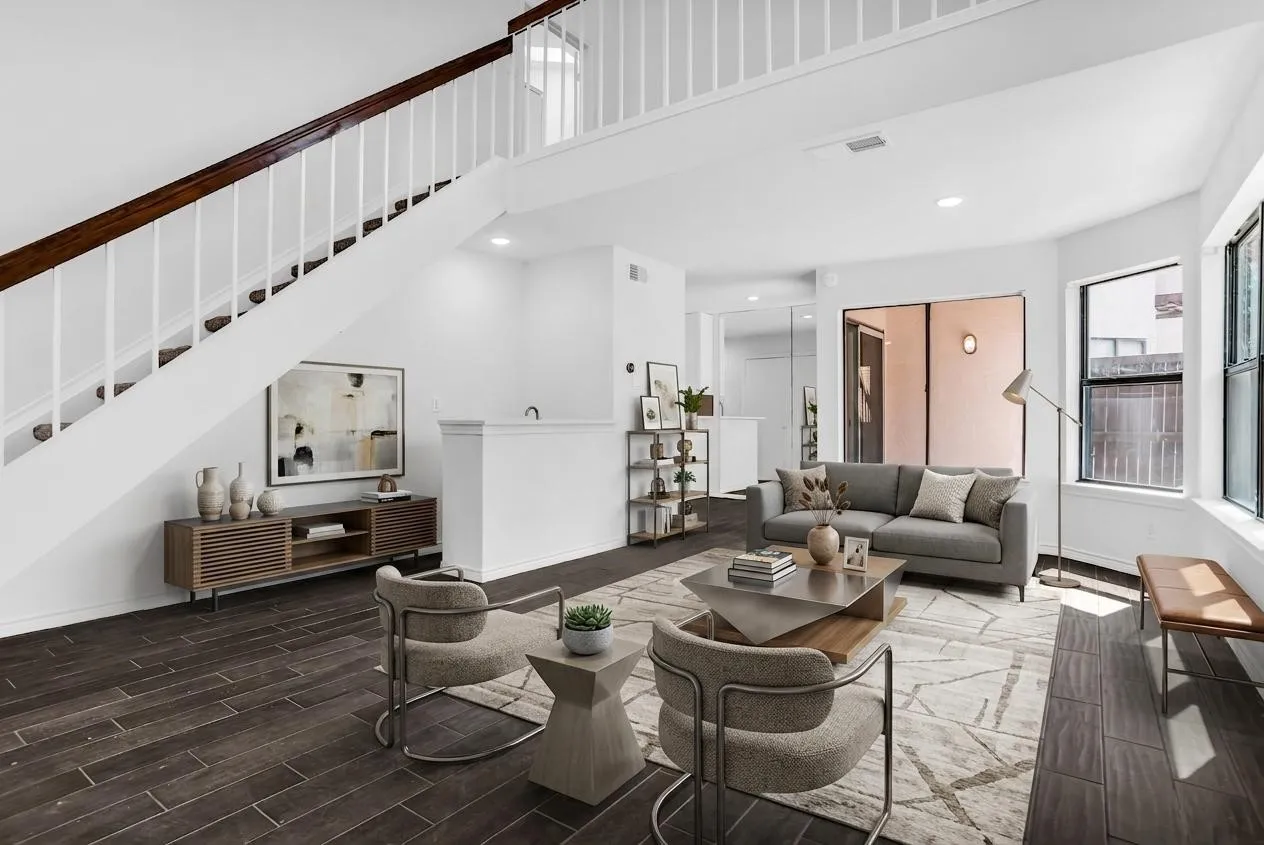 Open-concept living space featuring wood-finish flooring, a contemporary staircase with white balusters, recessed lighting, and a large window