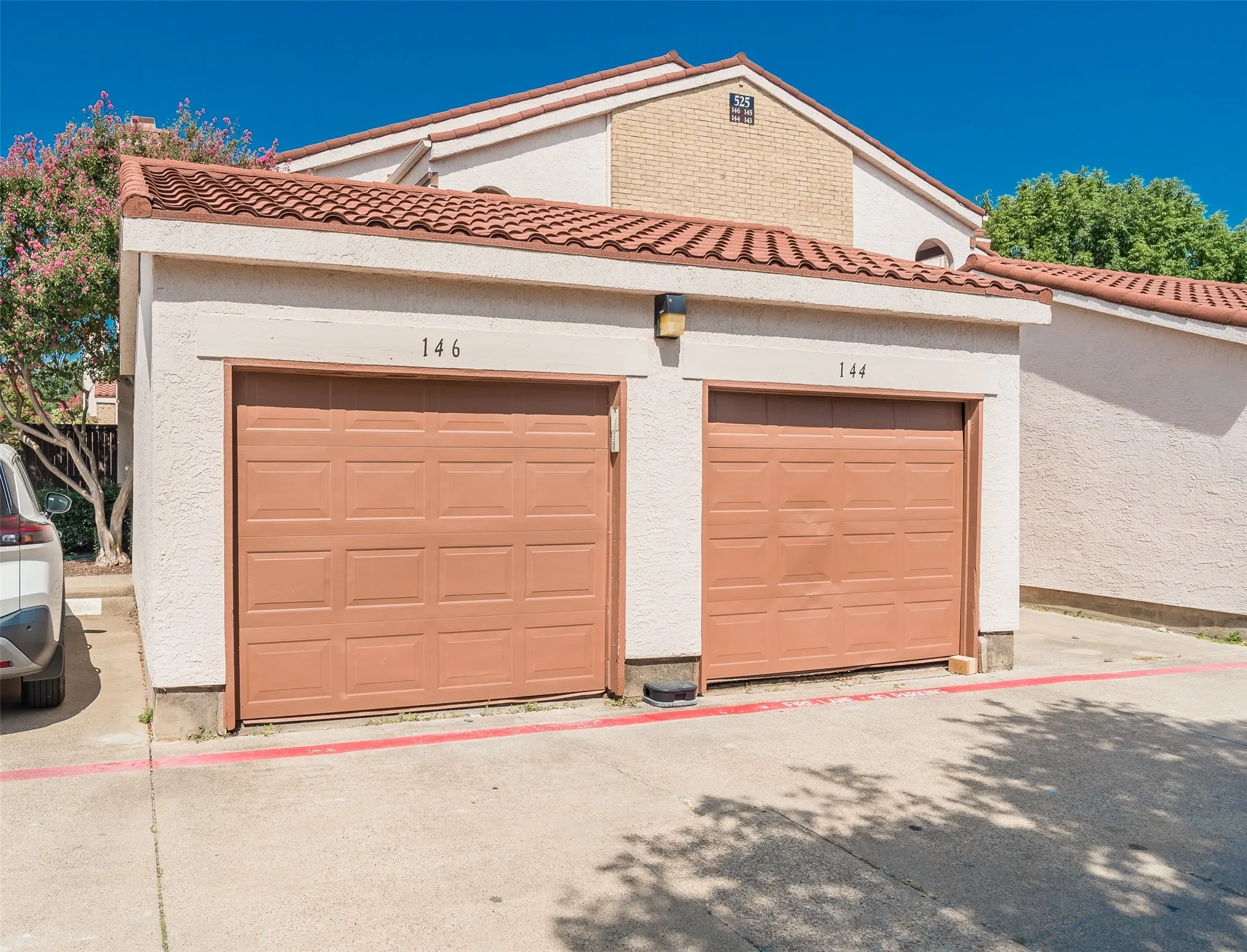 Stucco exterior featuring dual garage doors, a barrel tile roof, and a wall-mounted light fixture