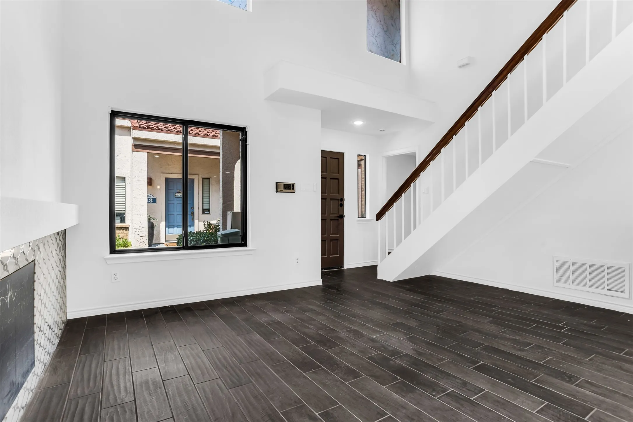 Vaulted ceilings, wood-finish flooring, staircase with dark wood handrail, fireplace with mosaic tile surround, and a dark wood-paneled entry door