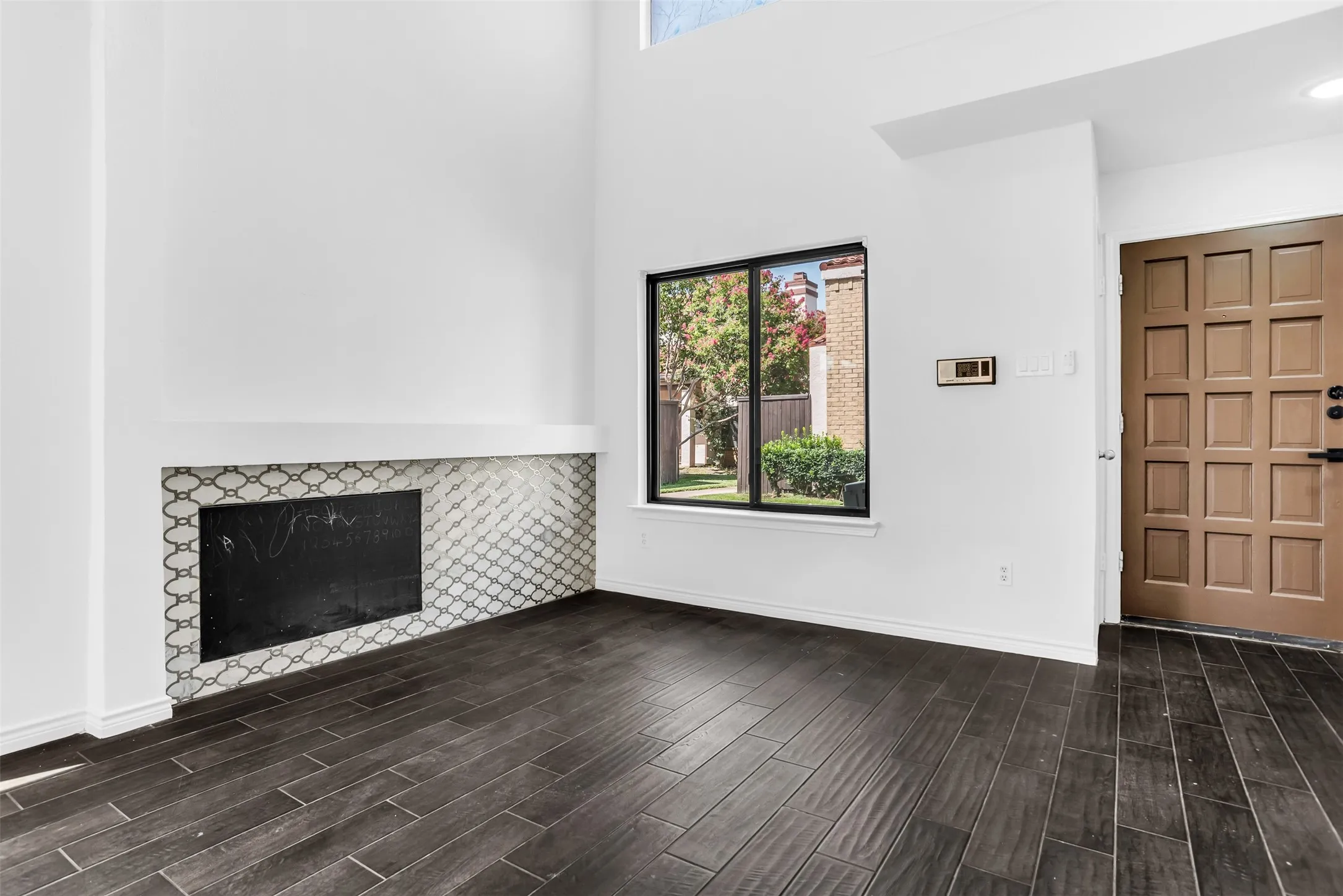 Open-concept living space featuring wood-finish flooring, a contemporary staircase with white balusters, recessed lighting, and a large window