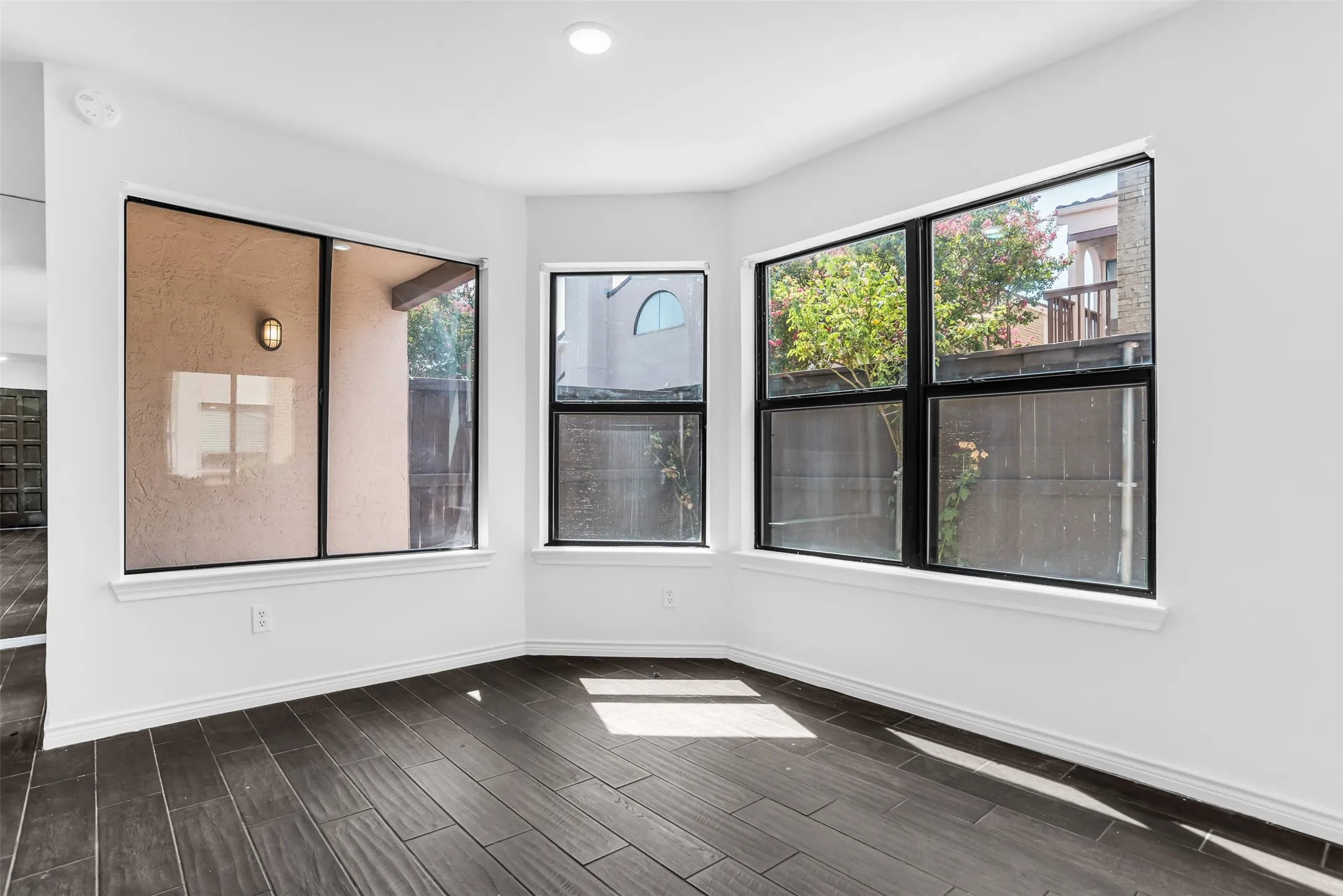 Multiple windows with dark frames, recessed lighting, and wood-finish flooring