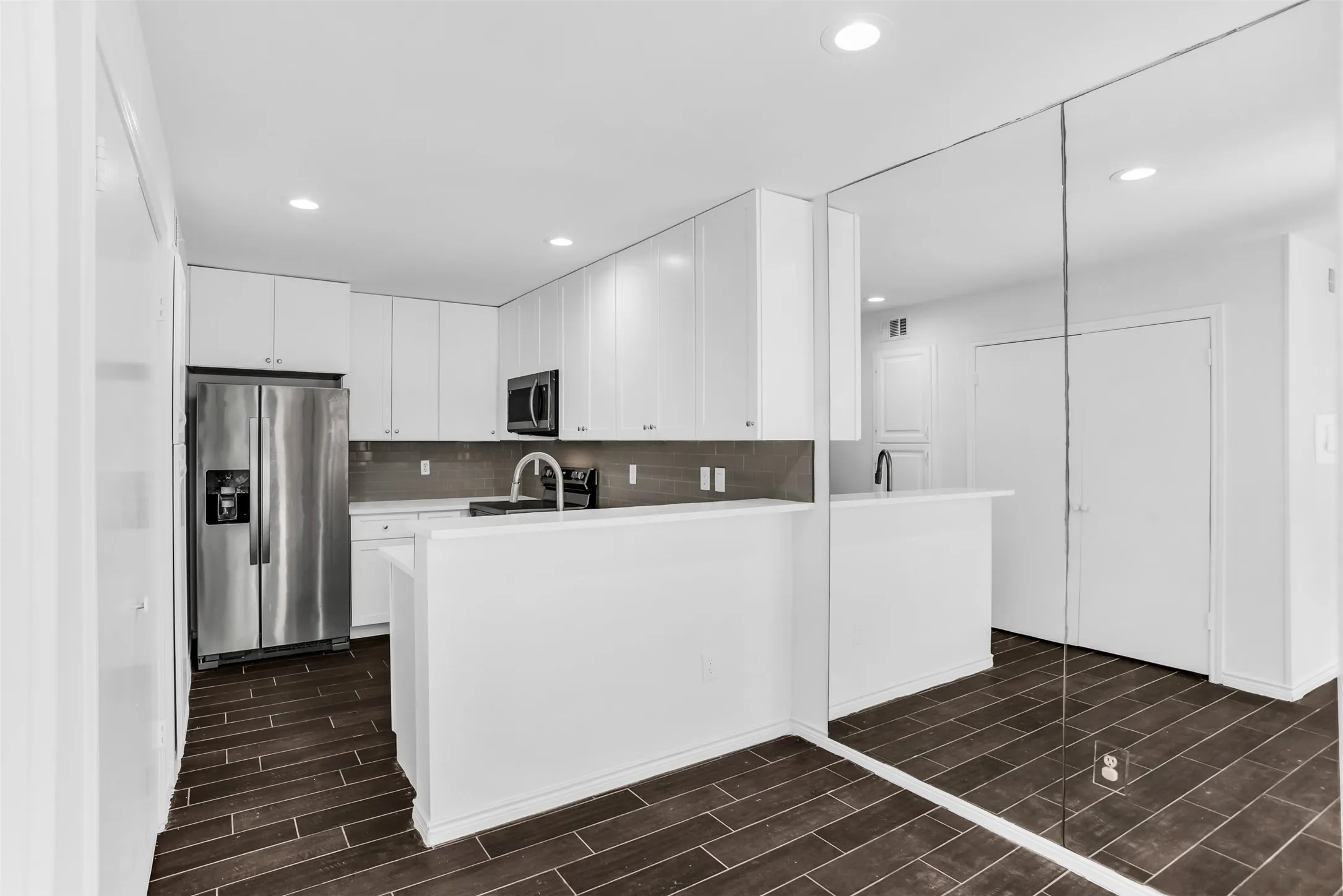 Kitchen featuring white cabinetry, stainless steel appliances, dark tile flooring, and recessed lighting