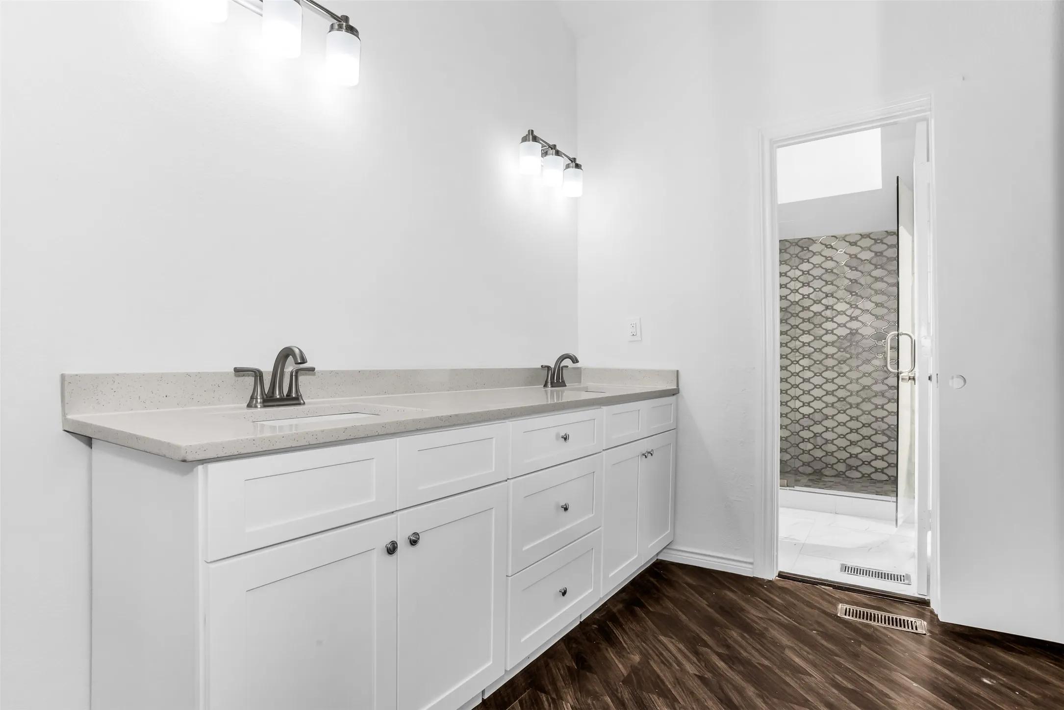 Dual vanity with white cabinetry, light-toned countertops, and brushed nickel fixtures