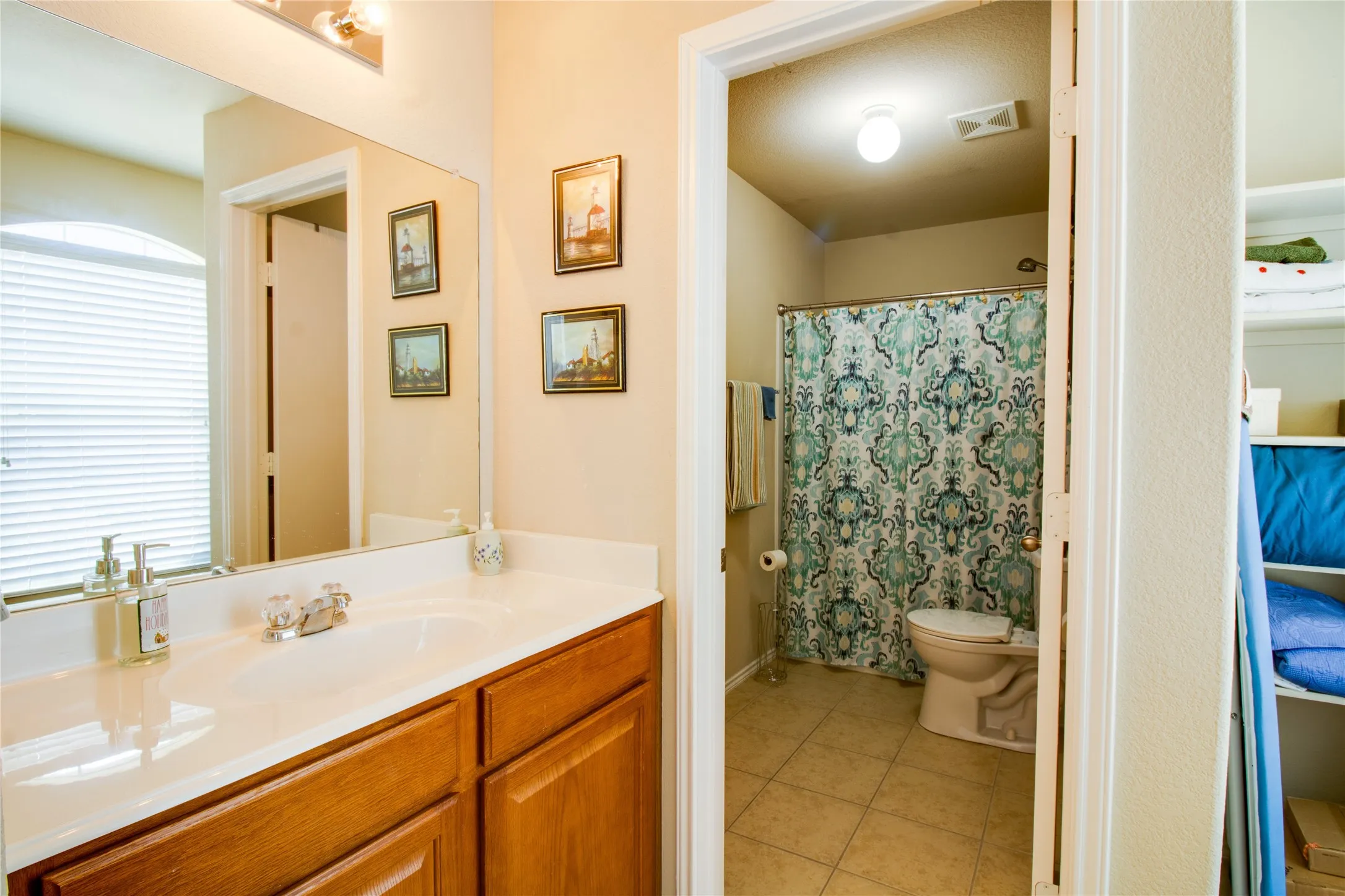 Bathroom vanity featuring a light-toned countertop, wood-finish cabinetry, and a large mirror