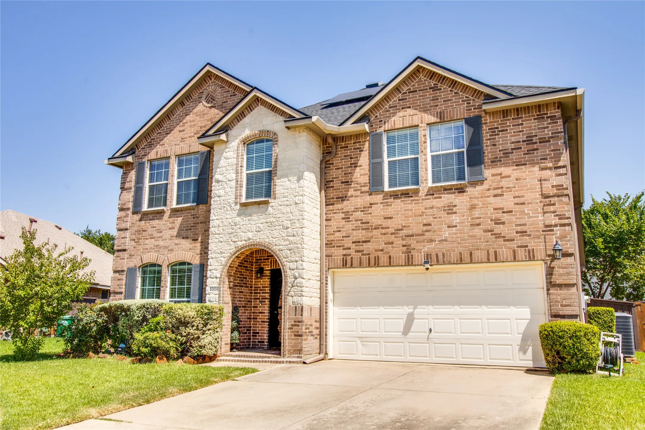 Two-story brick exterior with stone facade accents and arched entryway