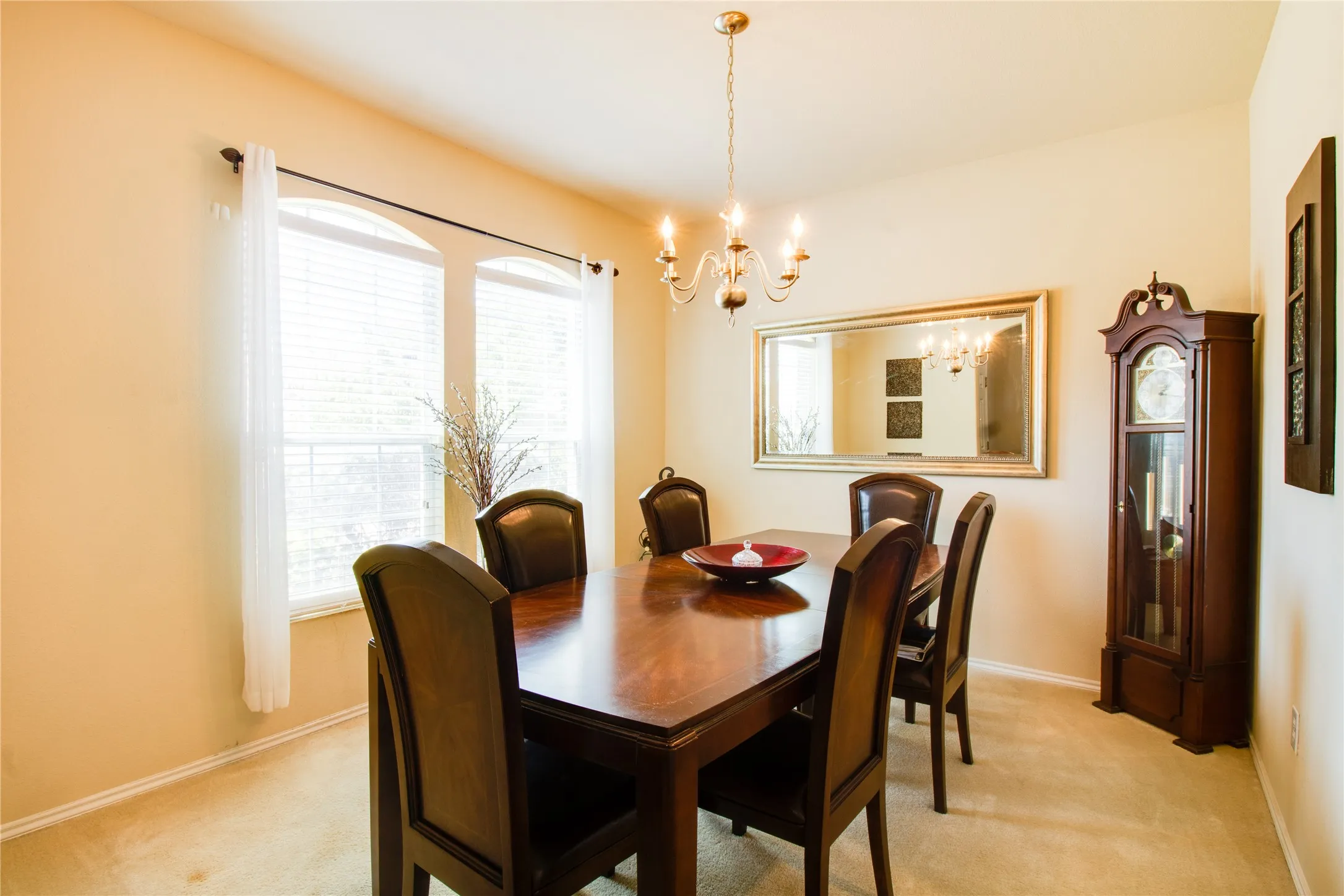 Room featuring two arched windows with blinds, a chandelier light fixture, and neutral wall tones