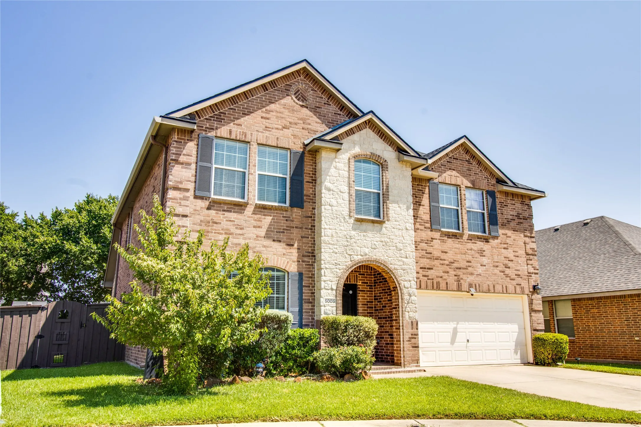 Two-story residence featuring a brick and stone facade with an arched entryway