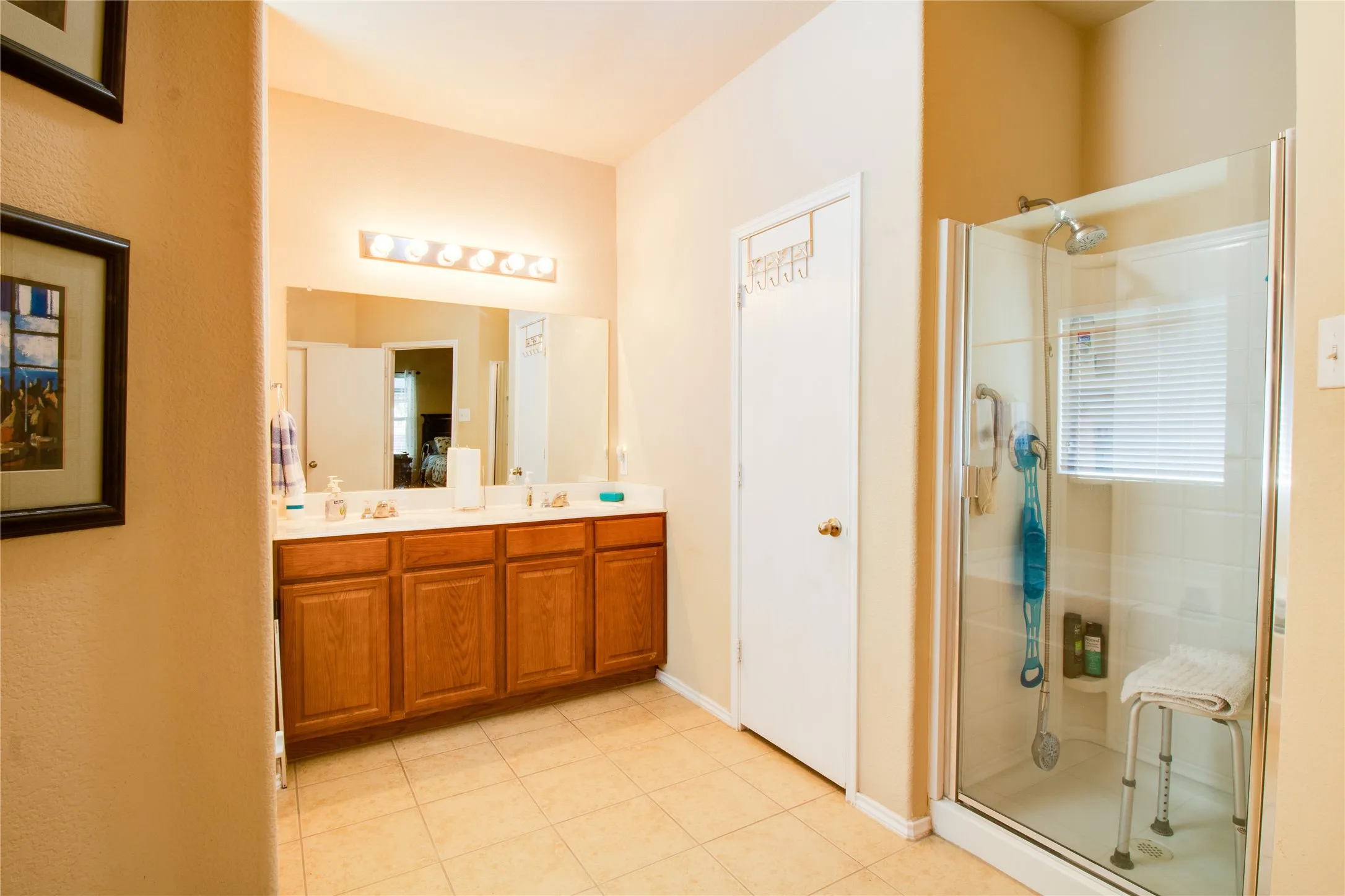 Bathroom featuring a dual vanity with wood-finish cabinetry and a framed glass shower enclosure